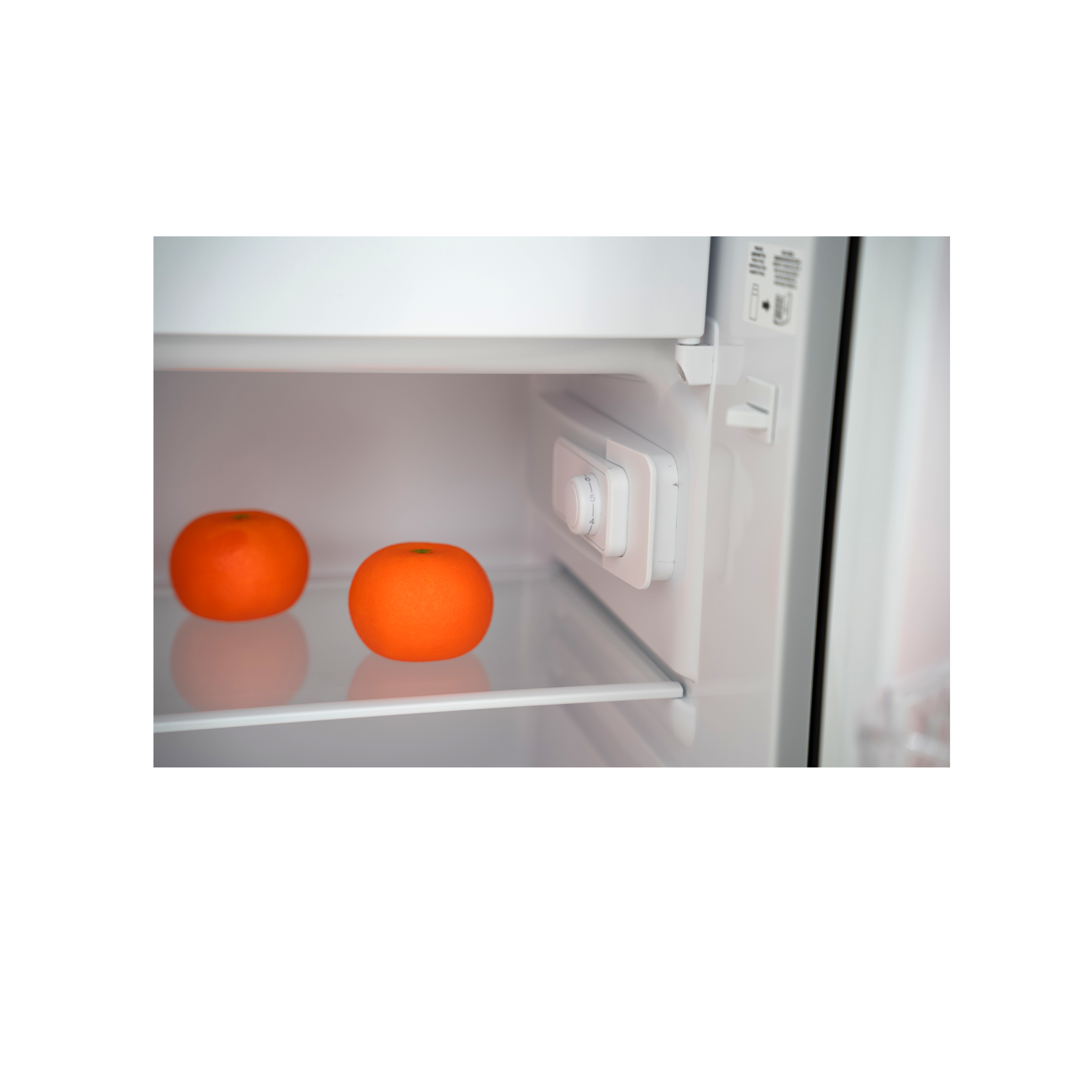 Deux oranges sur une étagère de réfrigérateur avec un cadran de température.