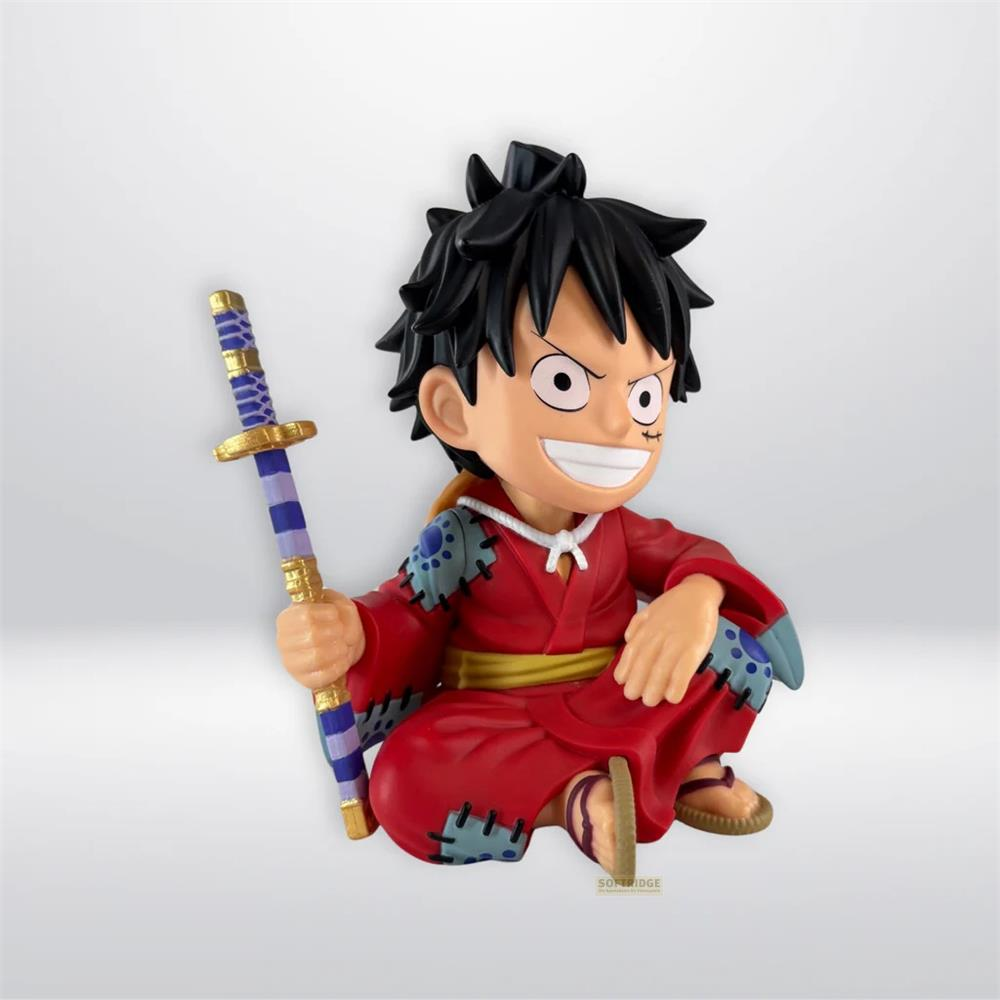 Figura chibi de Luffy con kimono rojo sostiene espada azul y dorada, sentado con piernas cruzadas.