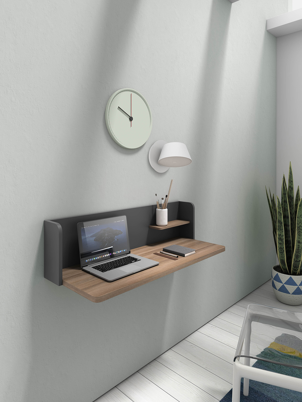 Un escritorio de pared con laptop, reloj, lámpara y planta en una habitación moderna.