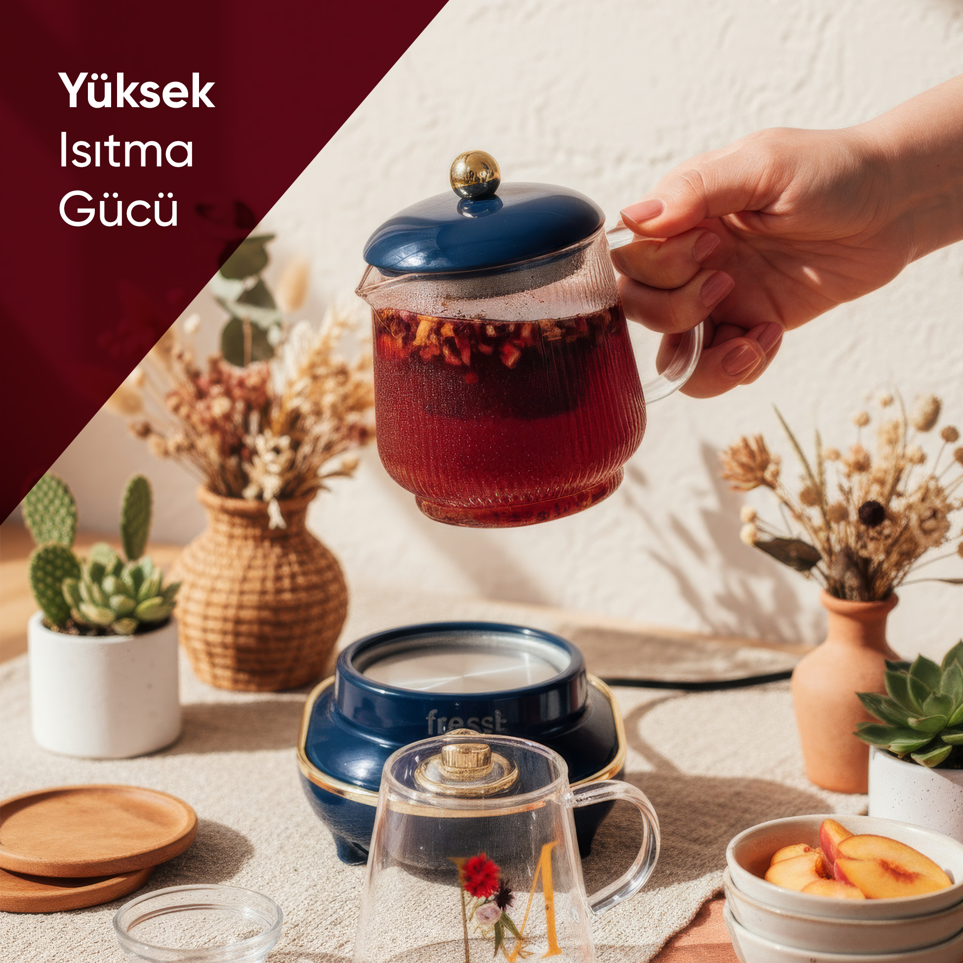 El, mavi bir ısıtıcı üzerinde çaylı mavi çaydanlık tutuyor. Bitkilerle süslenmiş.