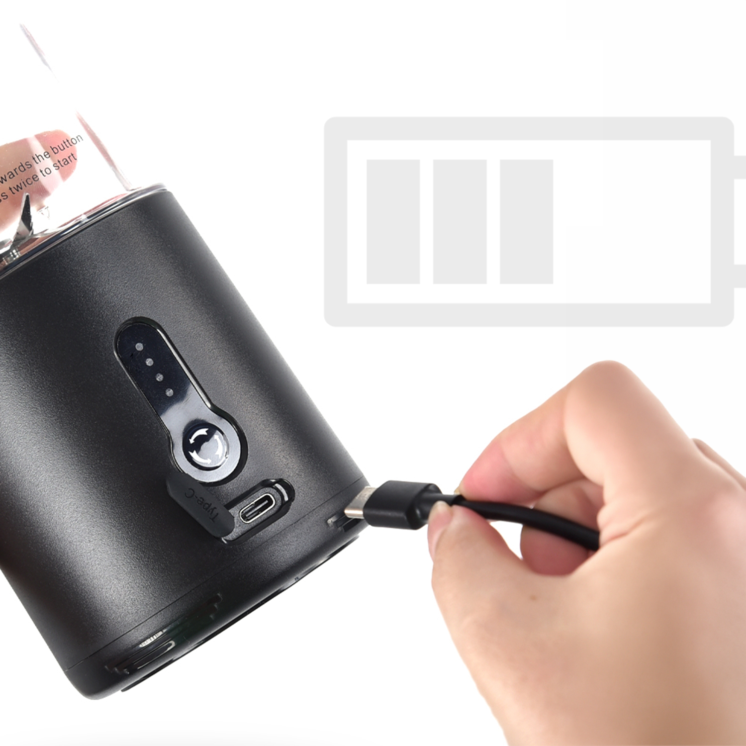 Una mano conecta un cable USB-C a una licuadora negra. Se ve un indicador de batería.