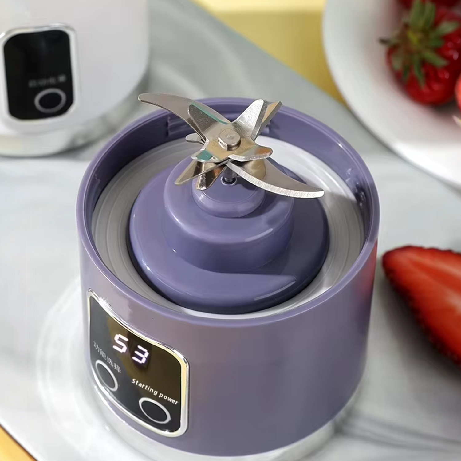 Batidora morada con cuchillas y fresas en un plato cerca.