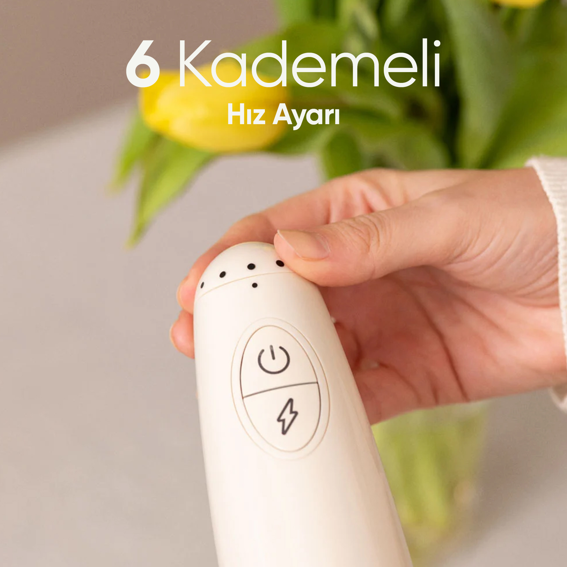 El, üzerinde açma/kapama ve şimşek sembolleri olan beyaz tek kullanımlık kamera tutuyor. Arkada sarı laleler.