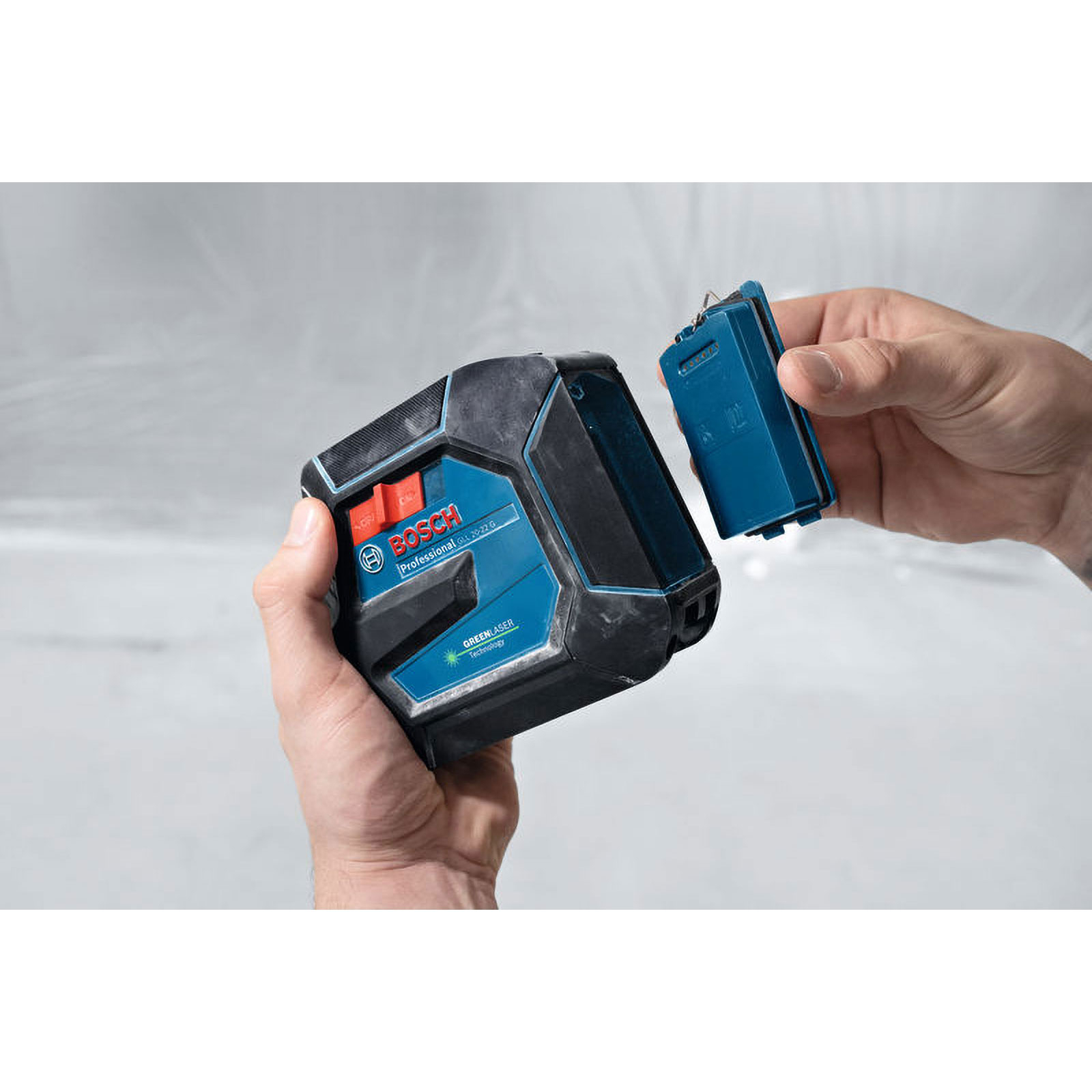 Mann setzt Akku in Bosch Laser-Wasserwaage ein.