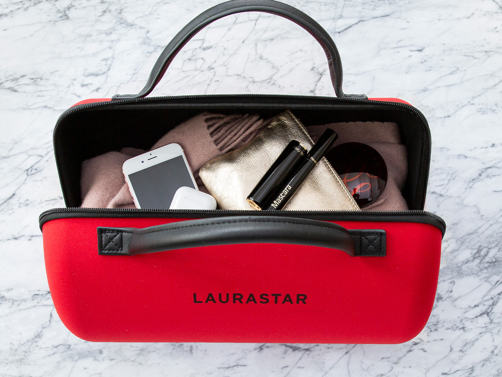 Rote LAURASTAR Tasche mit Henkeln, gefüllt mit Handy, Ohrhörern, Make-up.