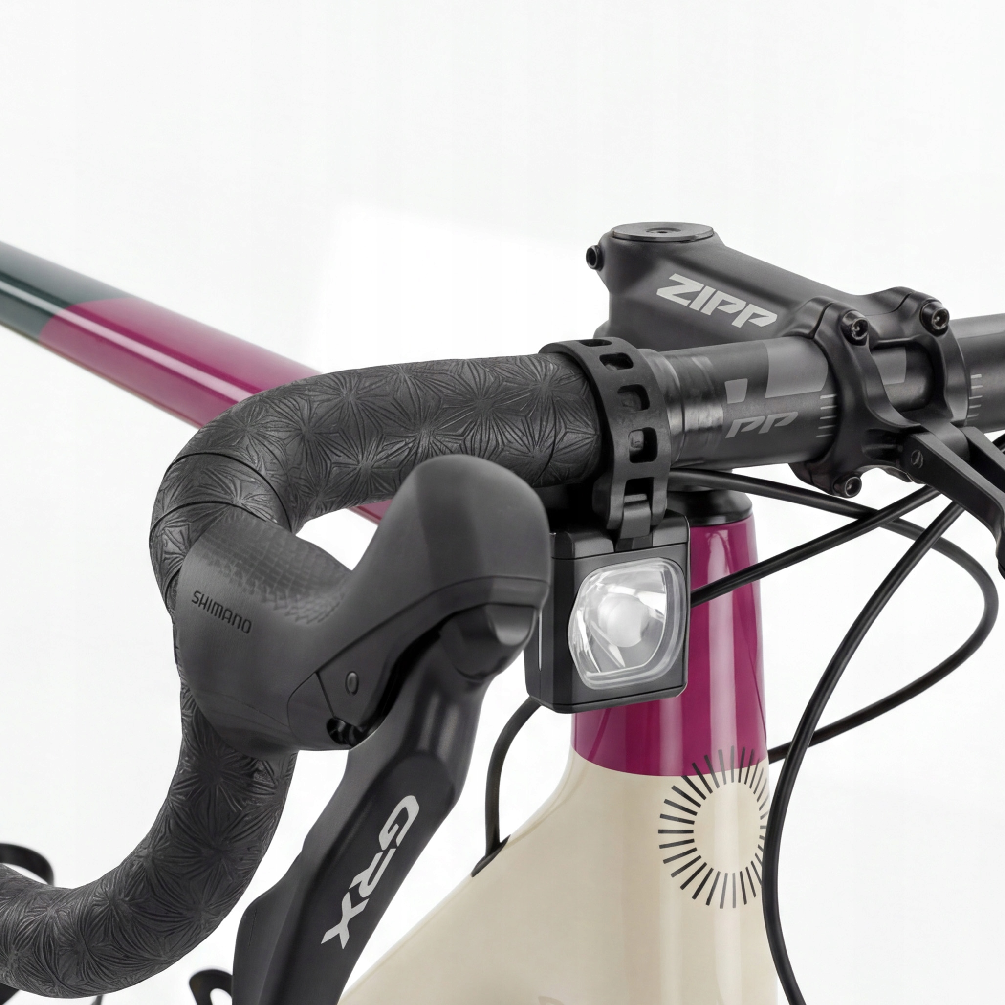 Zbliżenie kierownicy roweru ze światłem, manetką Shimano i mostkiem ZIPP.