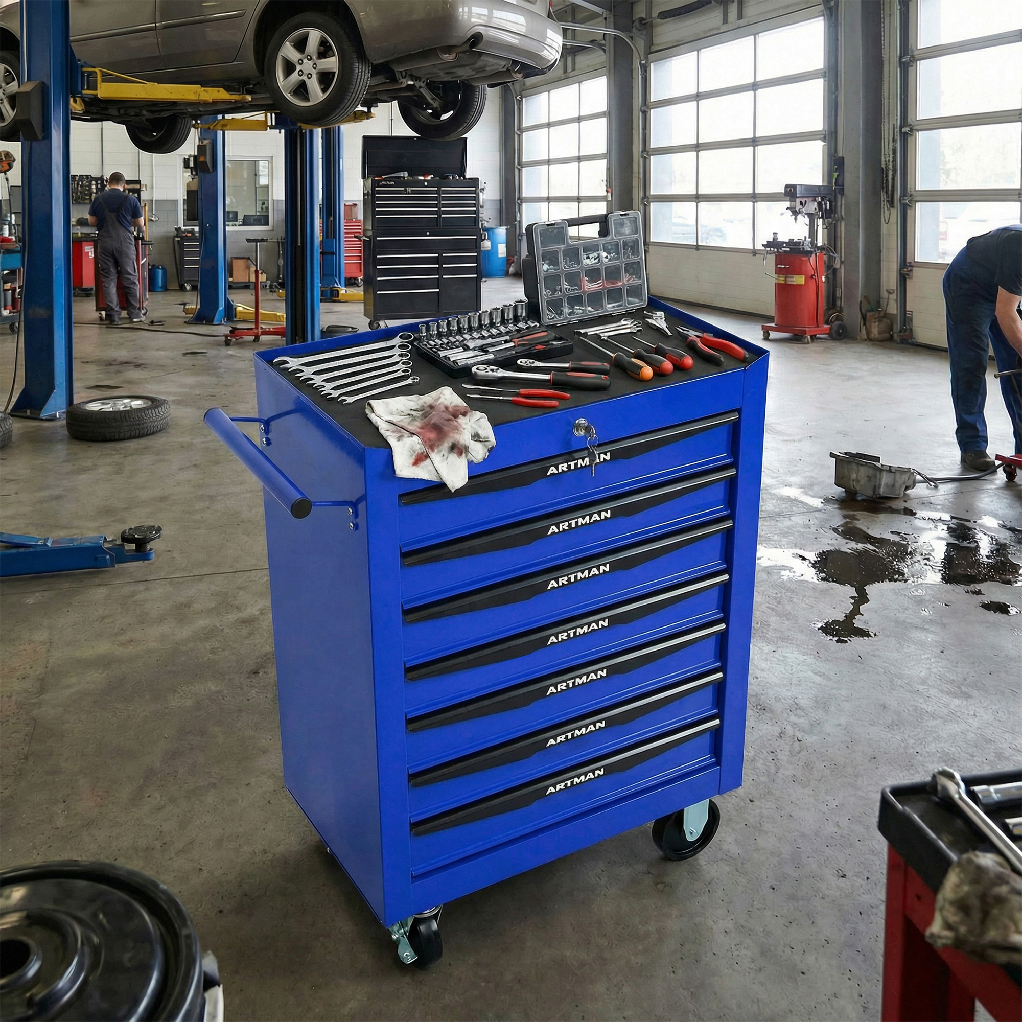 Ein blaues Werkzeugwagen steht im Vordergrund mit Werkzeugen. Autos sind auf Hebebühnen.