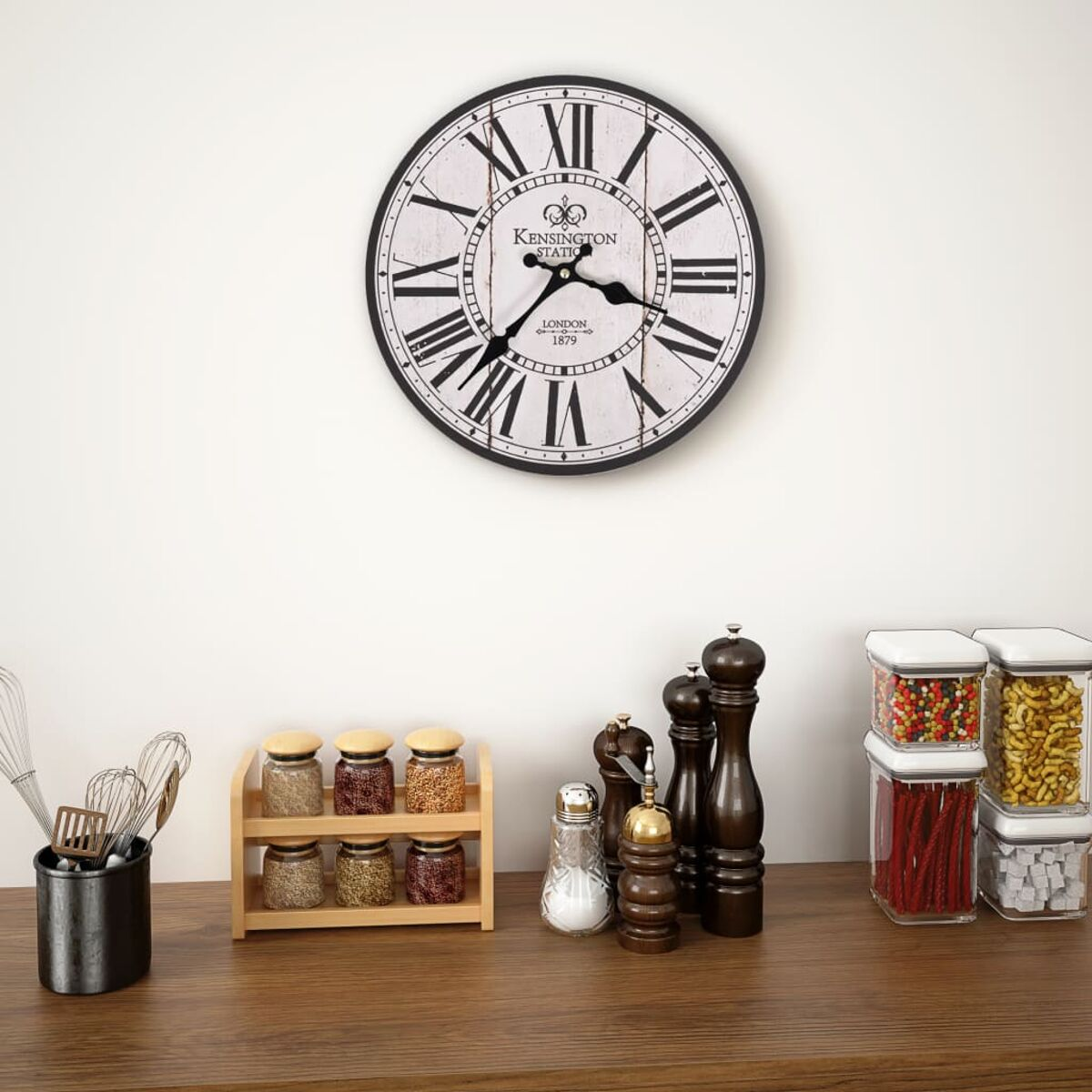 Eine Wanduhr über Gewürzgläsern, Mühlen und Vorratsbehältern auf einem Holztisch.
