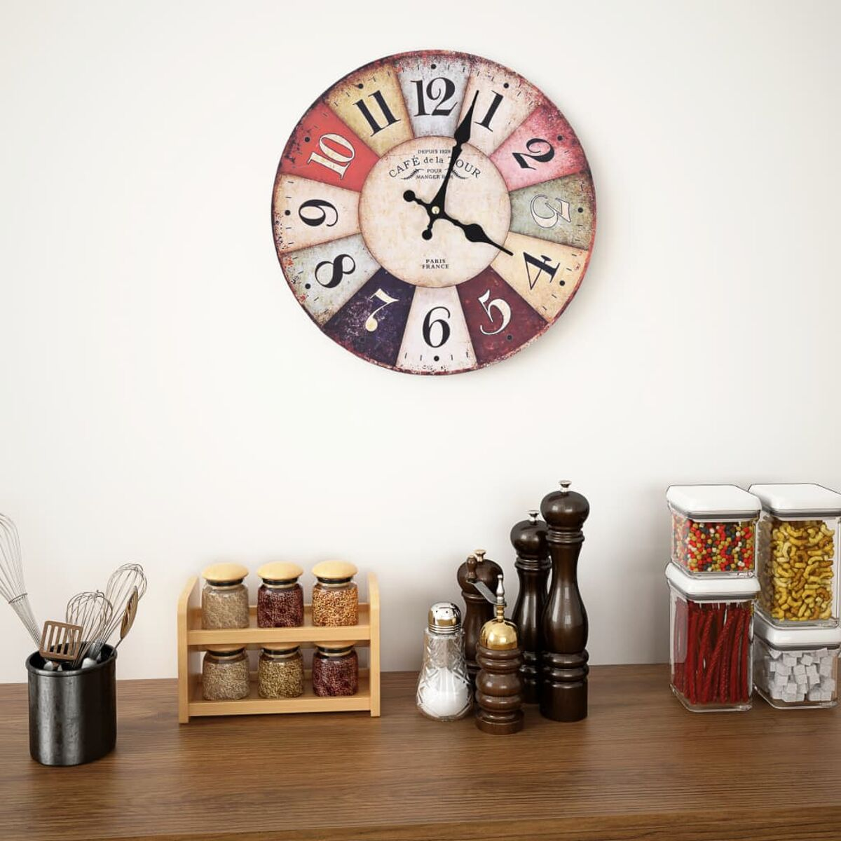 Eine Wanduhr über Gewürzgläsern, Mühlen und Vorratsdosen auf einem Holztresen.