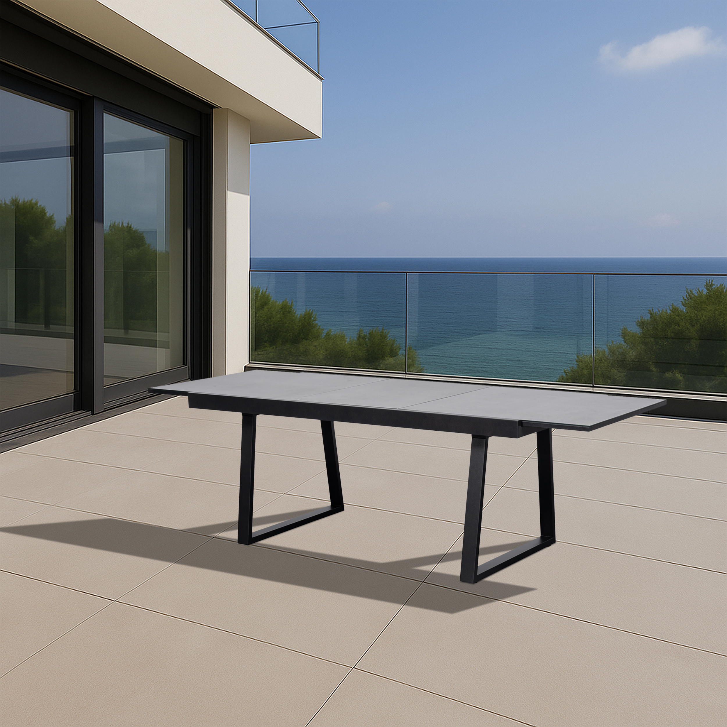 Moderner grauer Tisch mit schwarzen Beinen auf einer Terrasse mit Meerblick.