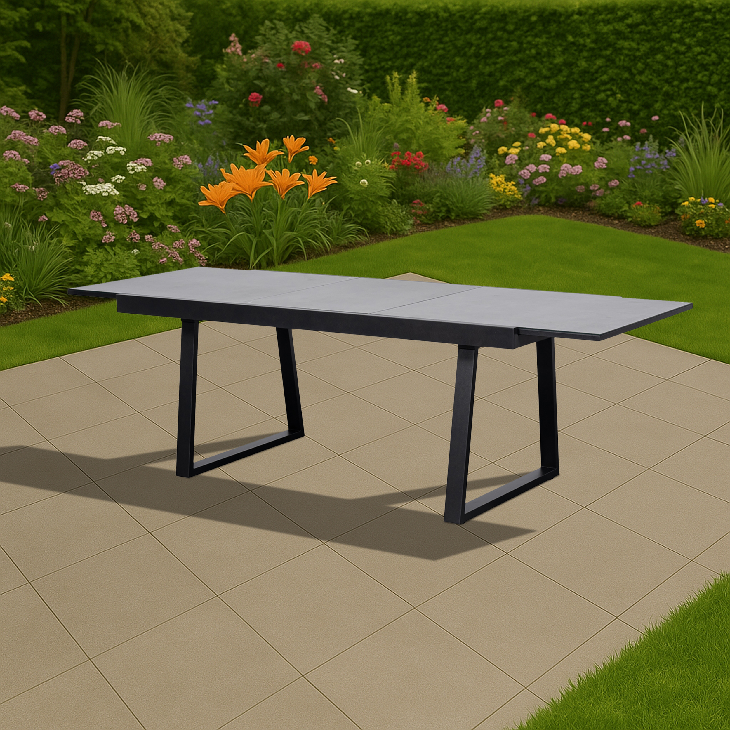 Ein grauer Tisch mit schwarzen Beinen steht auf einer Terrasse mit Blumen und Gras.