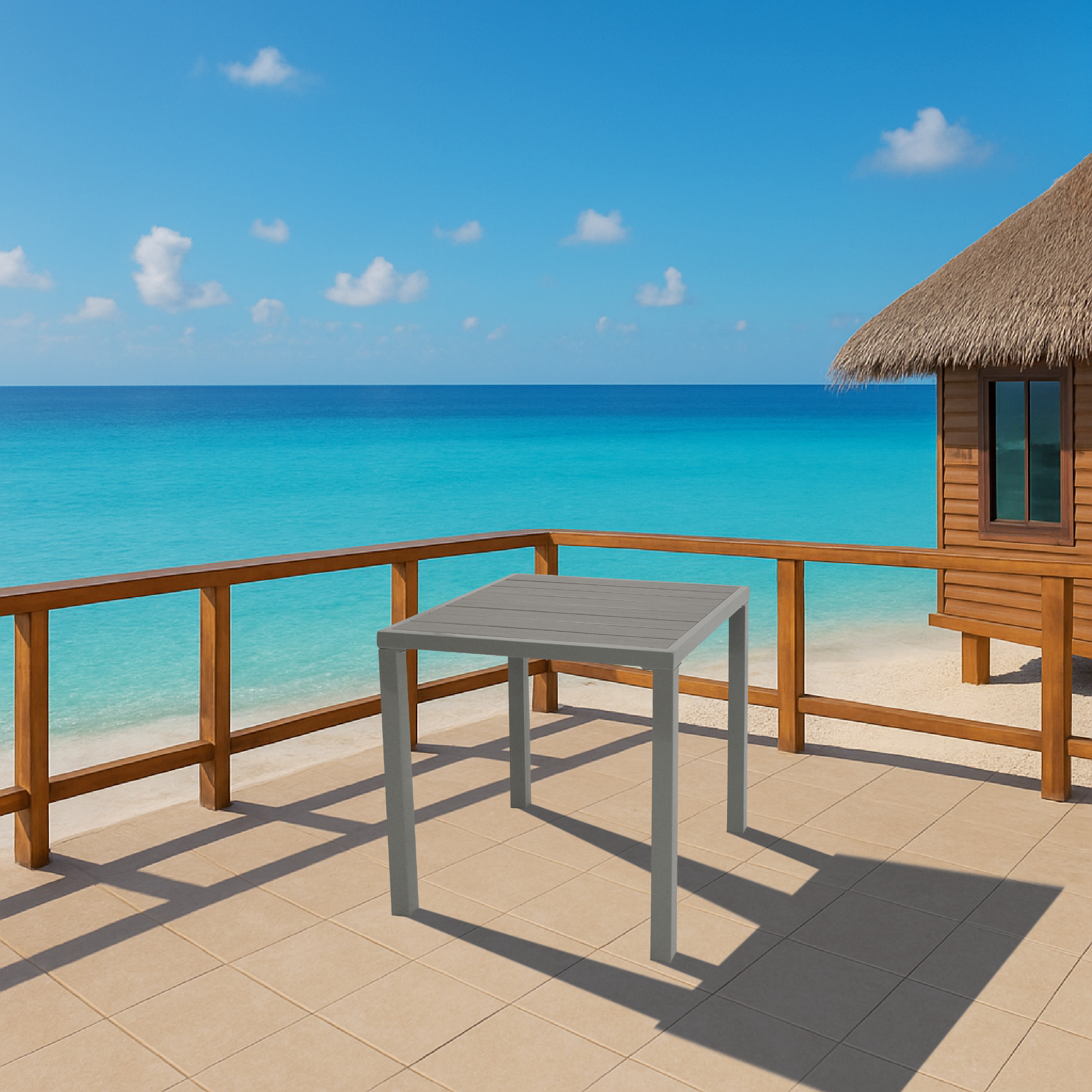 Ein grauer Tisch steht auf einer gefliesten Veranda am Meer, daneben ein Strohdachhaus.