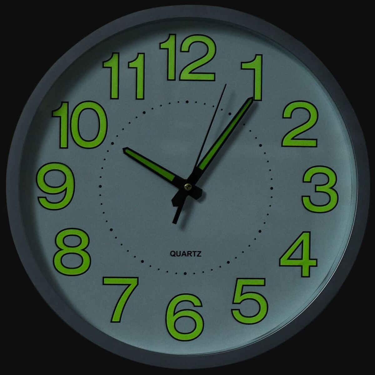 Eine graue Wanduhr mit leuchtgrünen Zahlen und Zeigern.