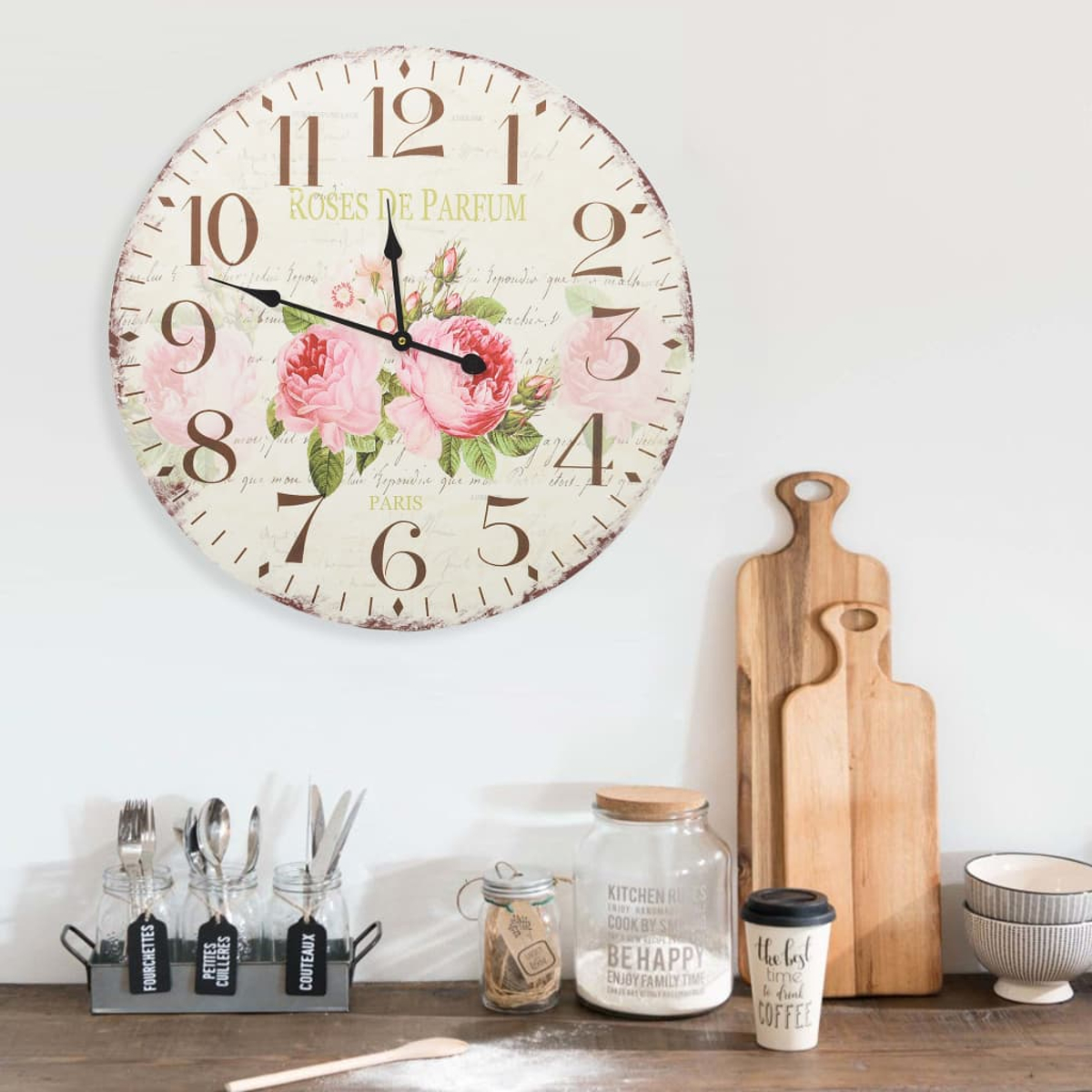 Eine Wanduhr mit rosa Rosen und französischer Schrift.