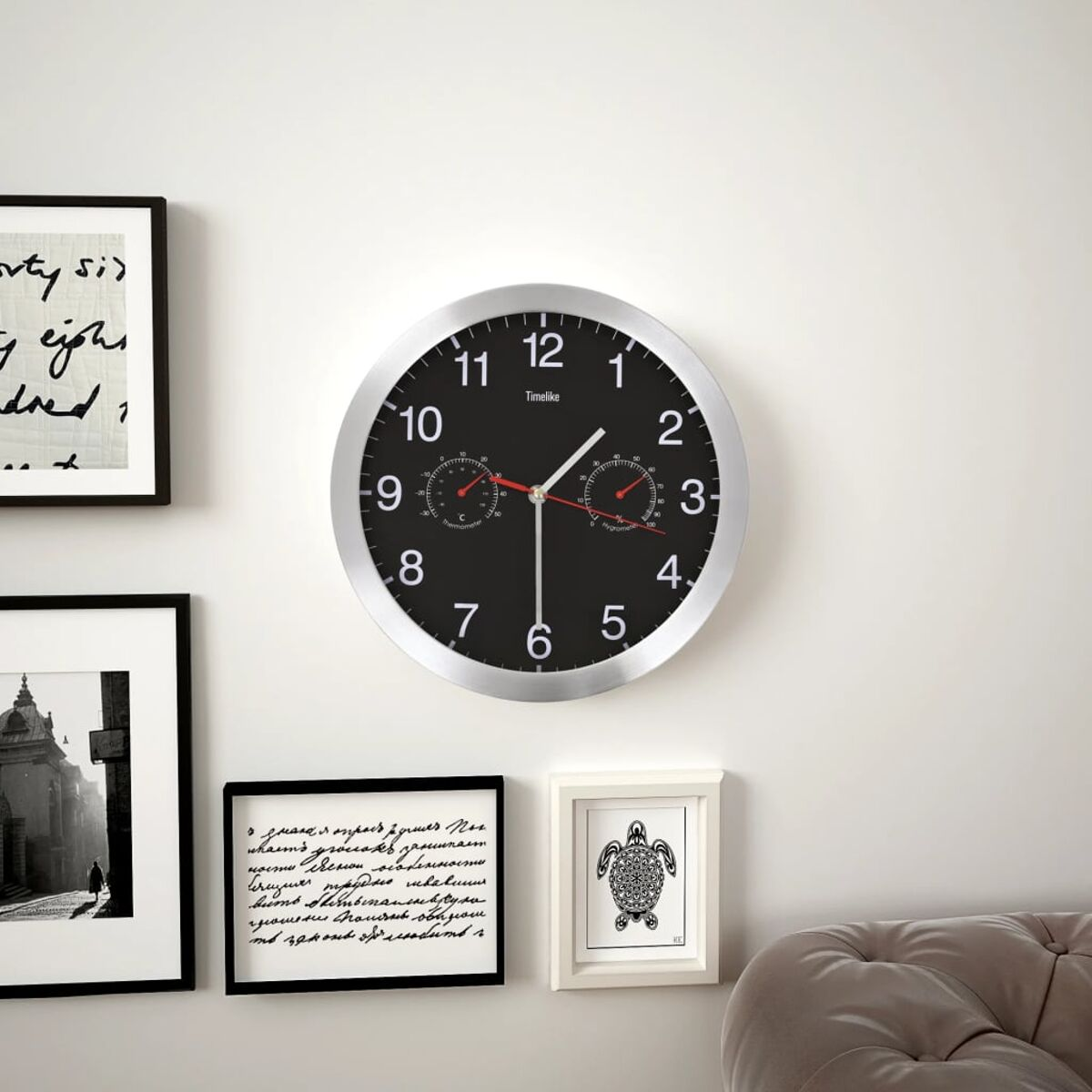 Eine Wanduhr mit silbernem Rahmen und schwarzem Zifferblatt mit Thermometer und Hygrometer.