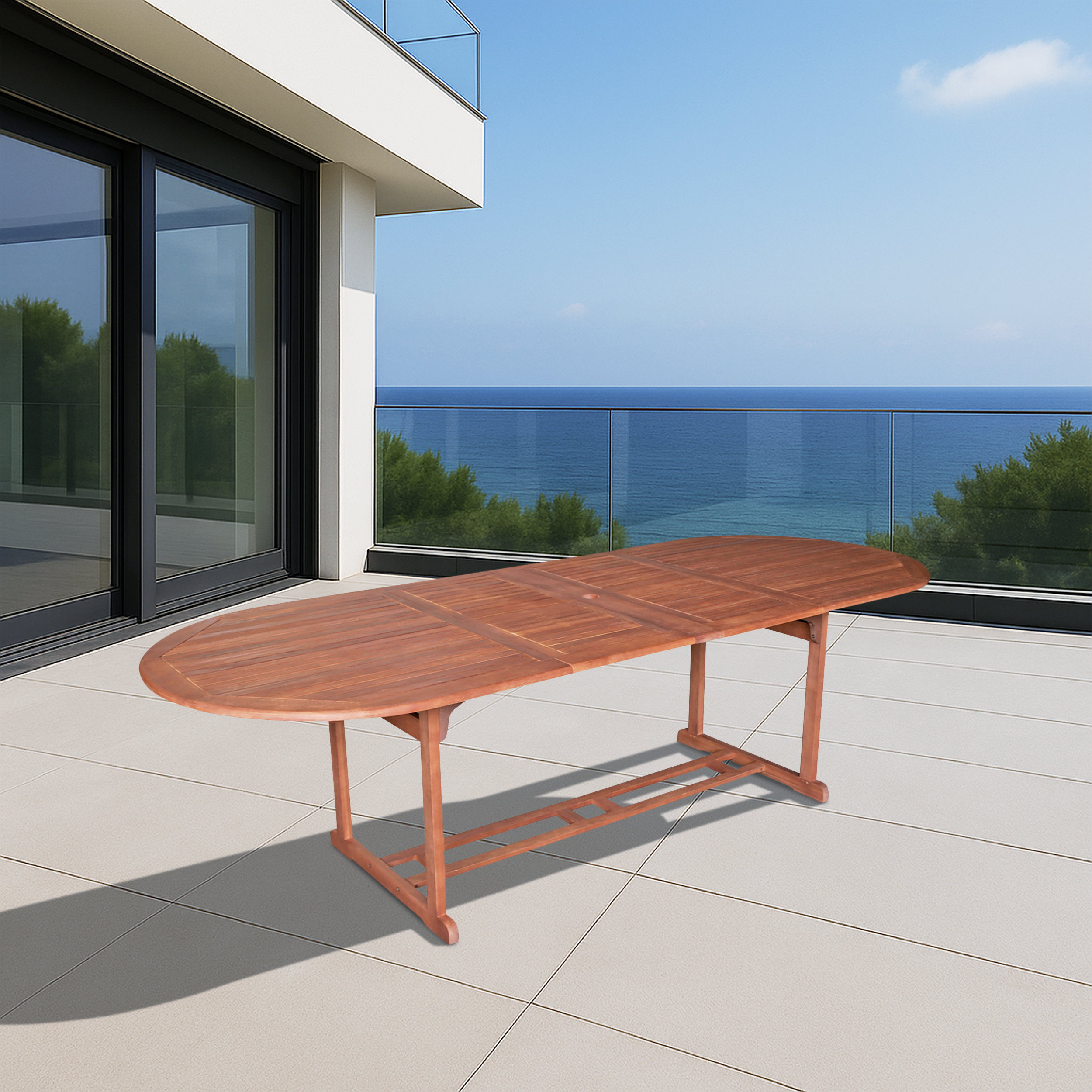Ein ovaler Holztisch steht auf einer gefliesten Terrasse mit Blick auf das Meer.