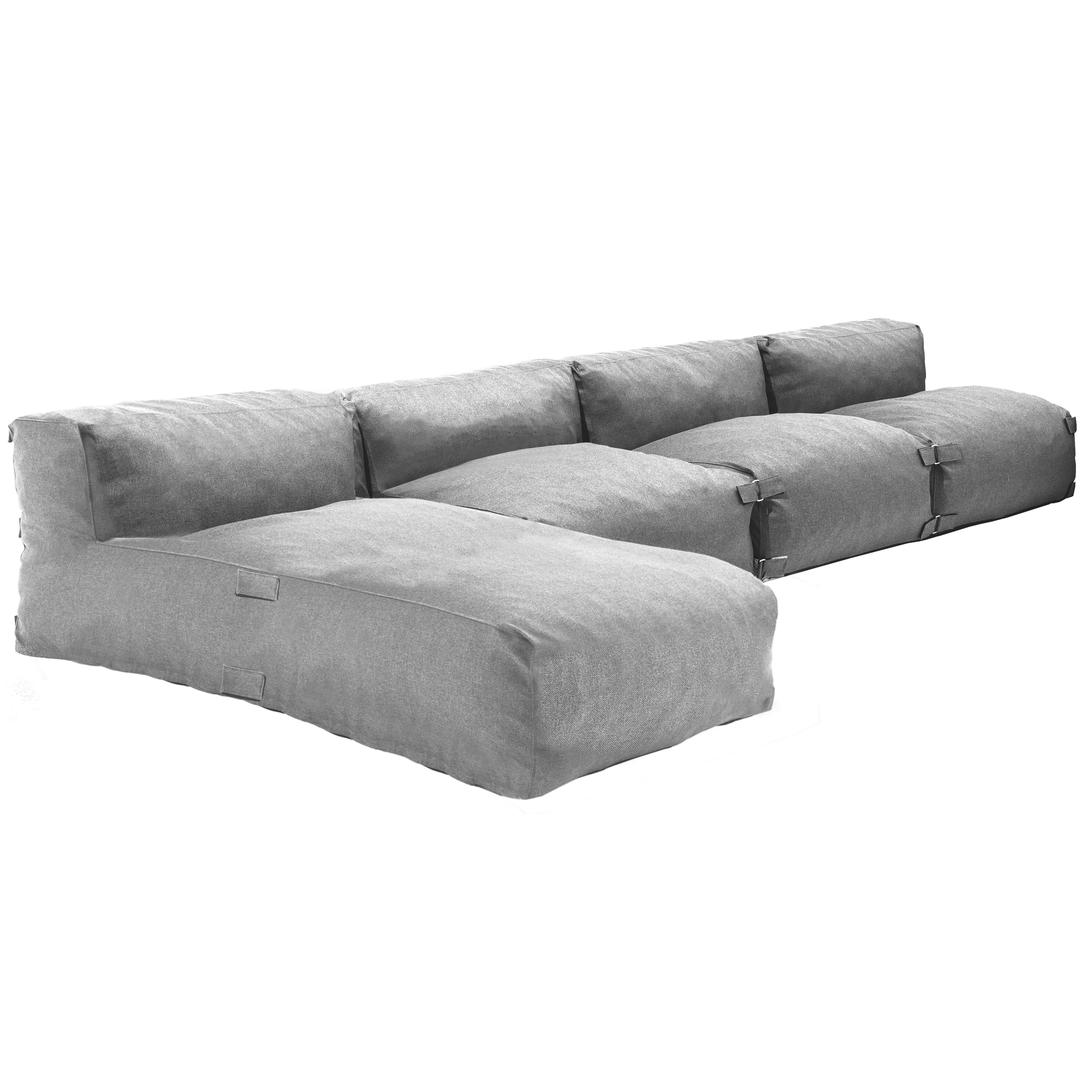 Graues Modulsofa mit breiten Kissen und kurzen Beinen, auf weißem Hintergrund.