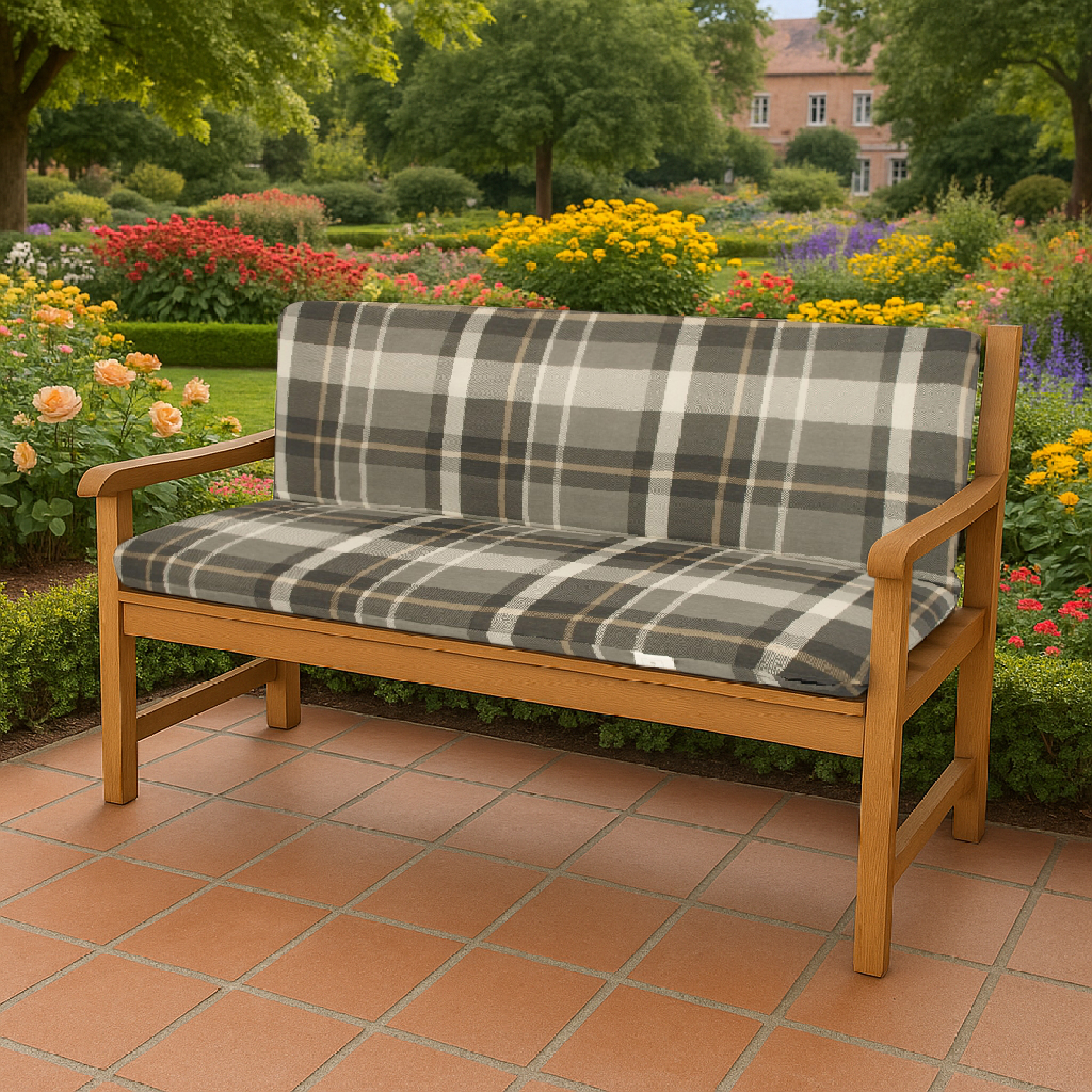 Holzbank mit karierter Polsterung auf einer Terrasse vor einem blühenden Garten.