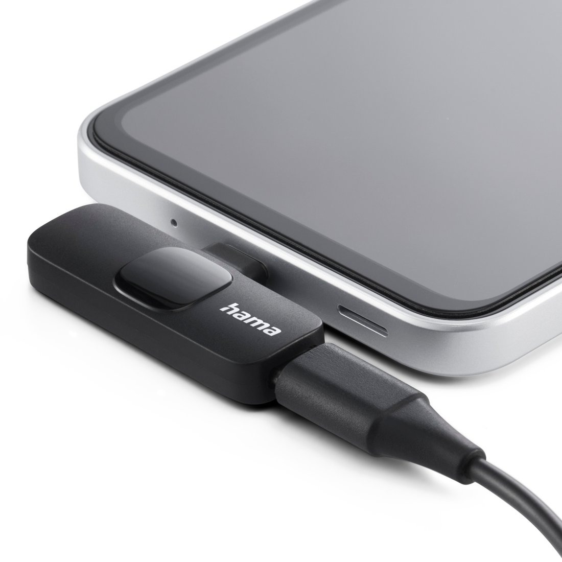 Czarny adapter Hama z przyciskiem jest podłączony do srebrnego smartfona.