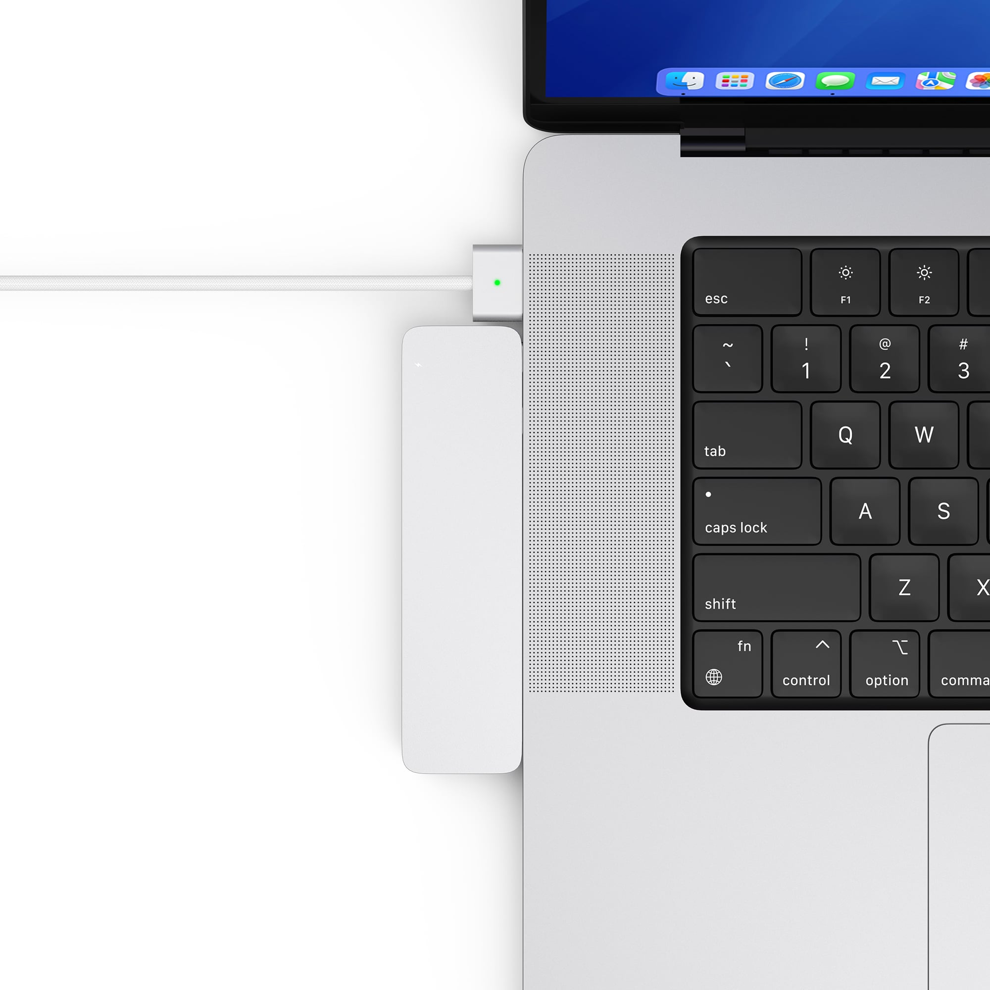A white adapter is connected to a MacBook, with a green light.