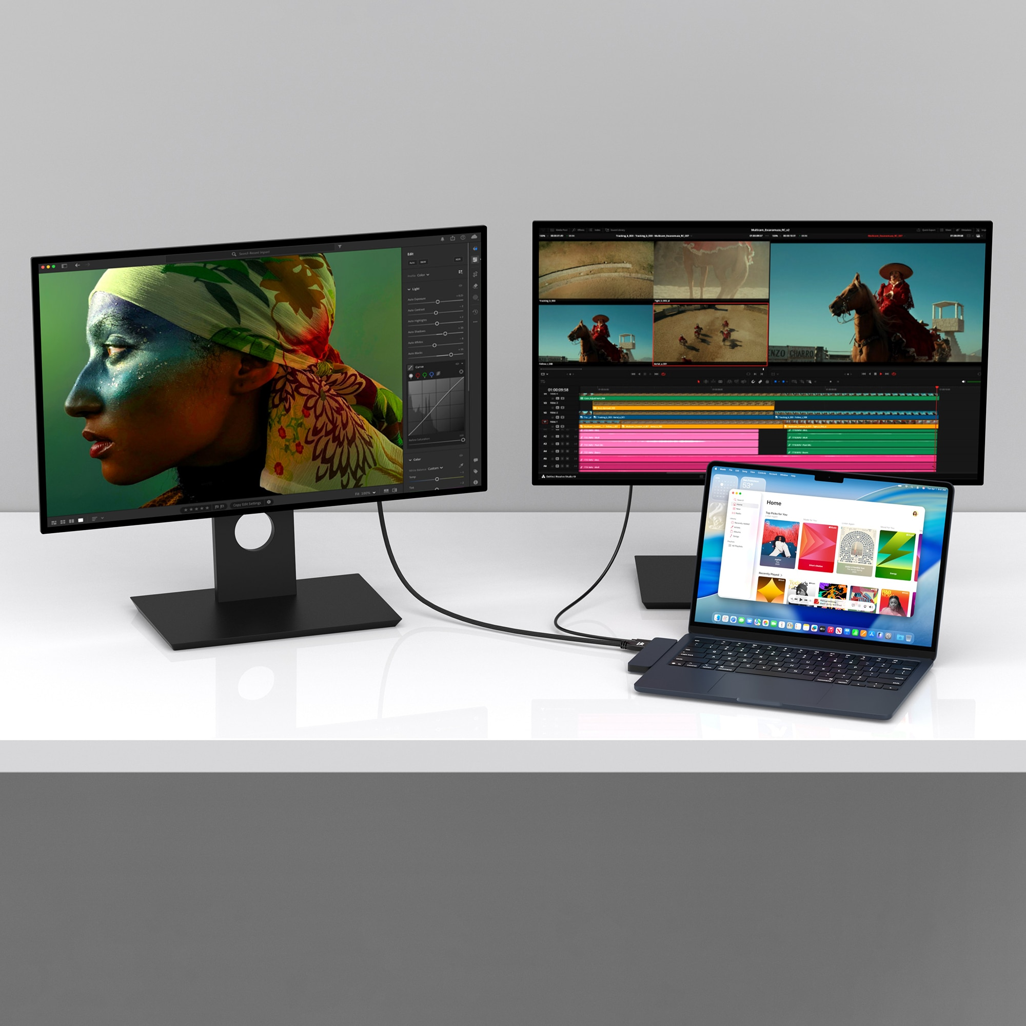 A laptop is connected to two monitors. One shows a portrait, the other video editing software.