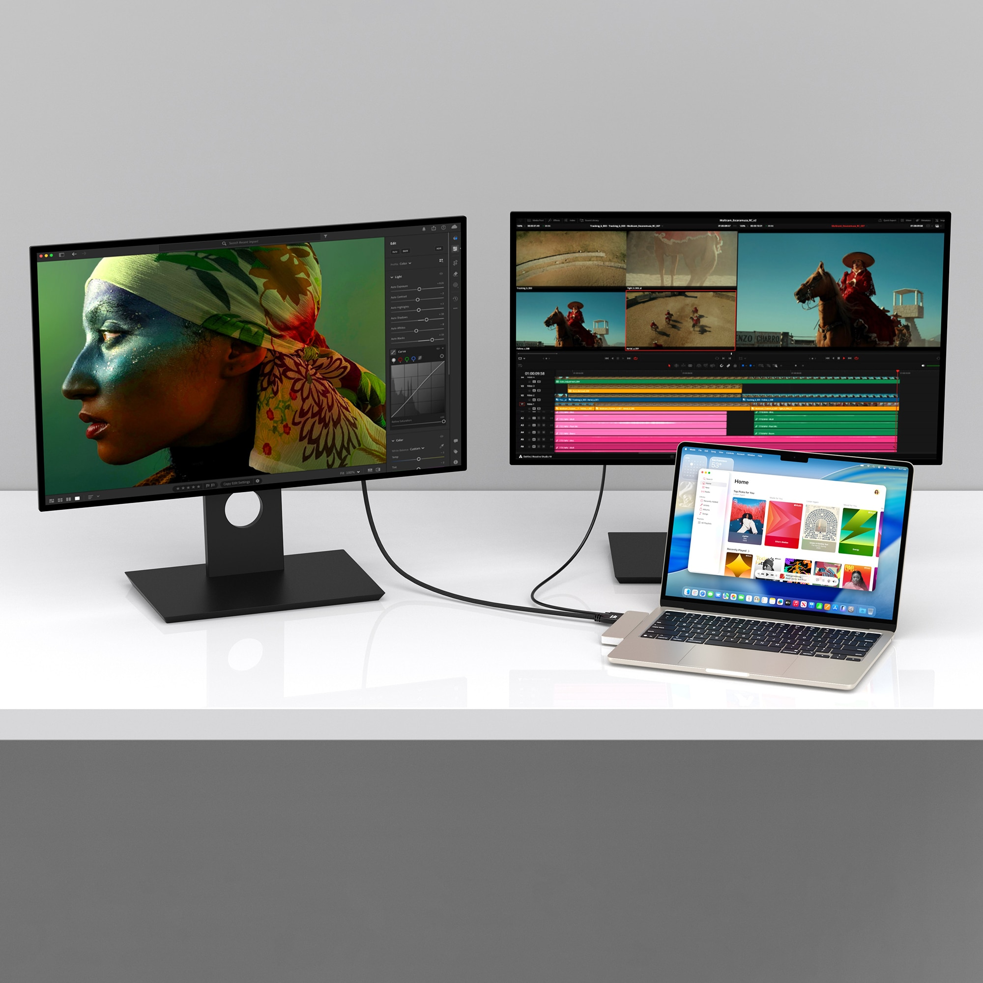 A laptop and two monitors display editing software and videos.