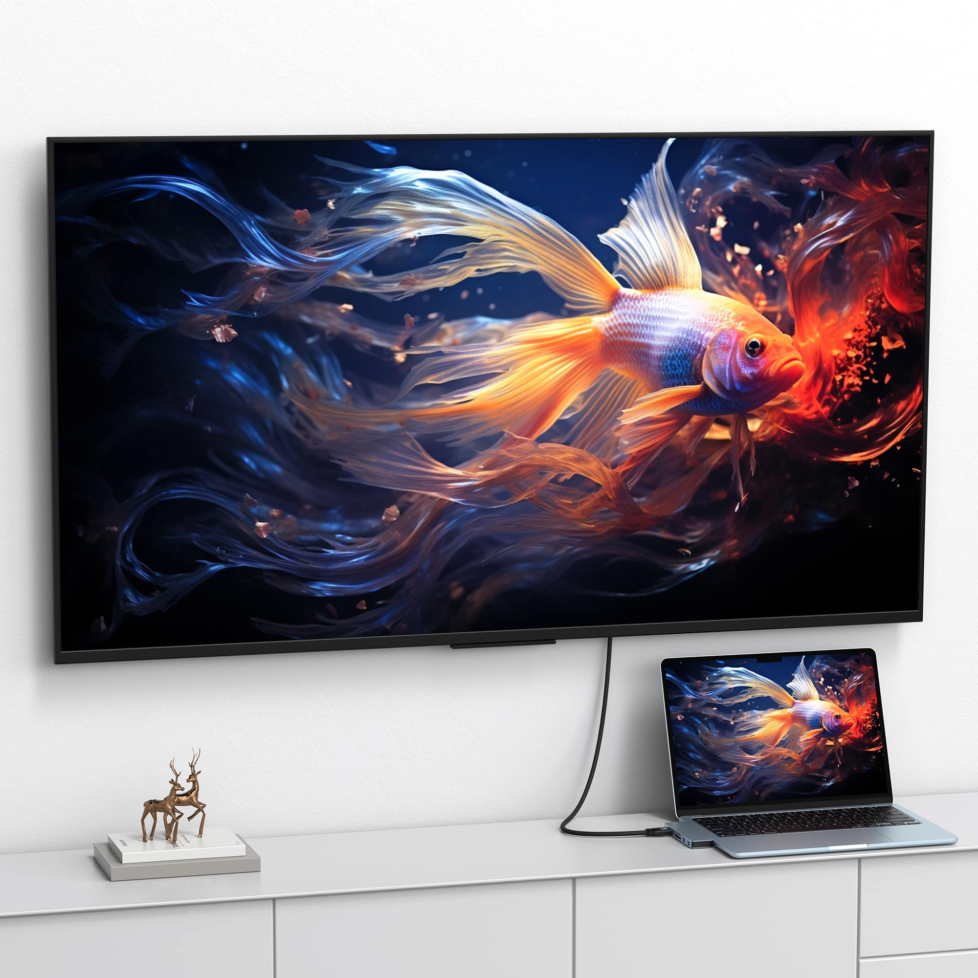 A TV and laptop display a vibrant goldfish swimming in a dark, fluid environment.