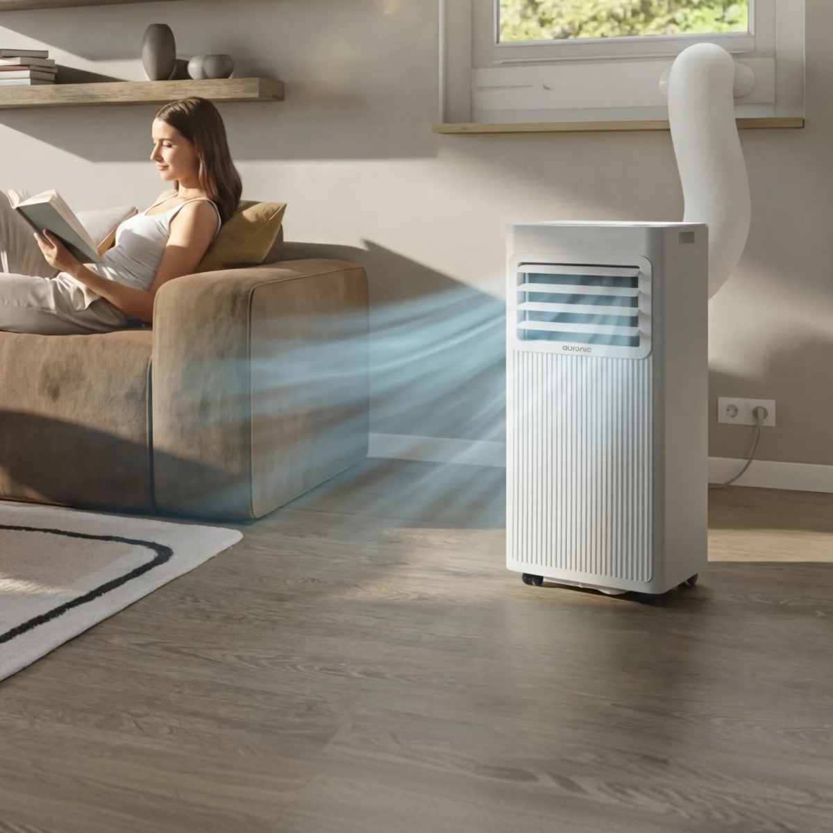 Woman reads book on sofa, portable AC unit blows cool air.