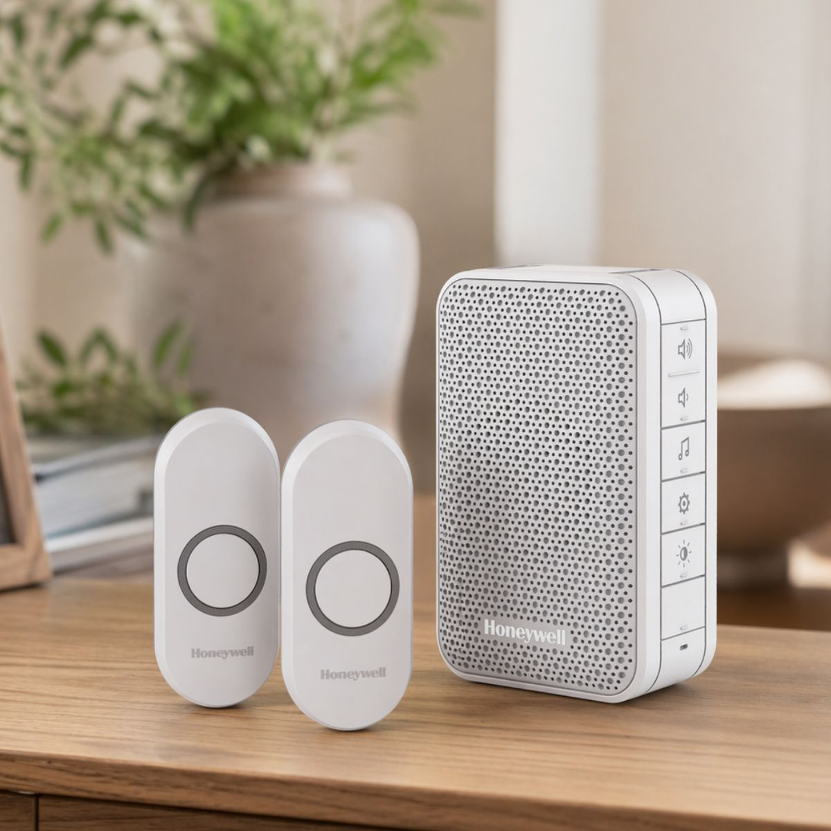 Deux boutons de sonnette Honeywell blancs et un récepteur blanc sur une table en bois.