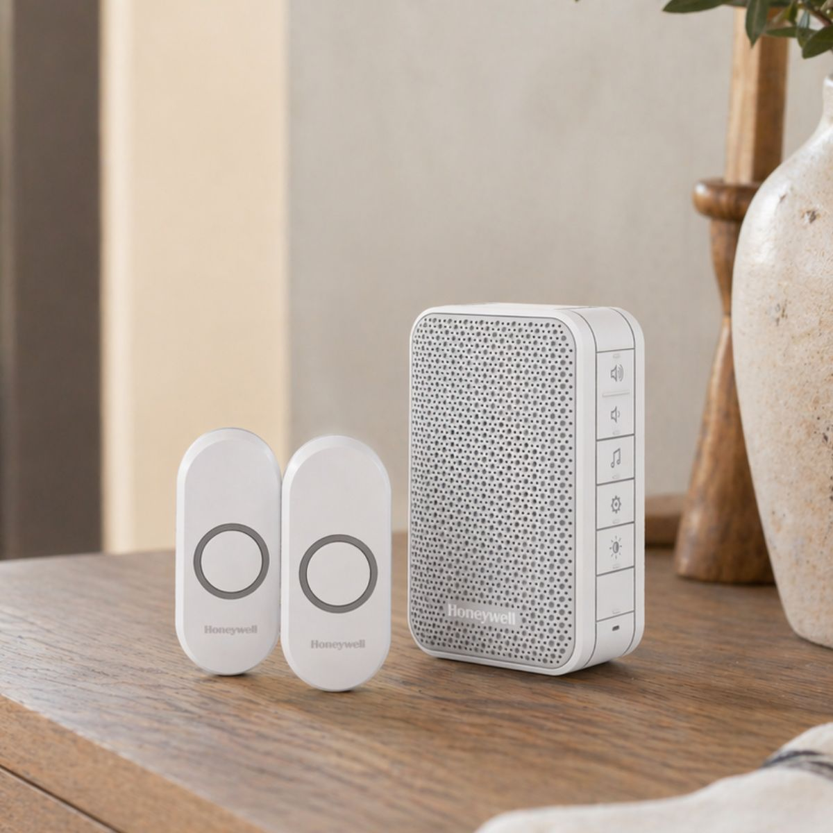 Deux sonnettes Honeywell blanches et un haut-parleur blanc sur une table en bois.