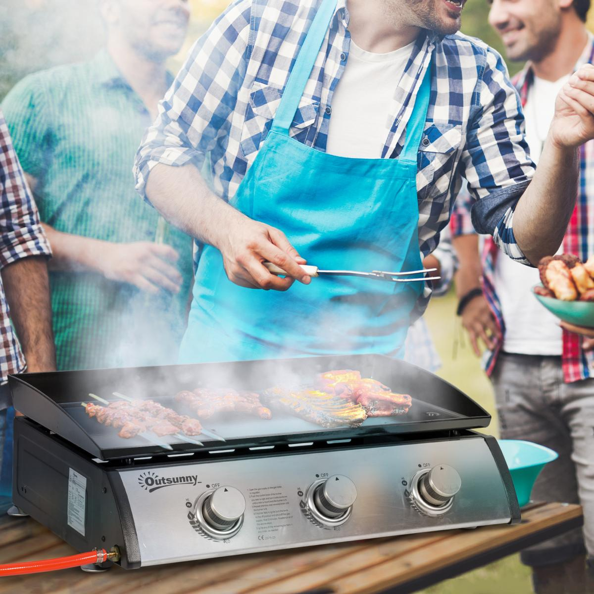 Männer grillen Fleisch auf einem Gasgrill mit Rauch und einem blauen Schürzen-Grillmeister.