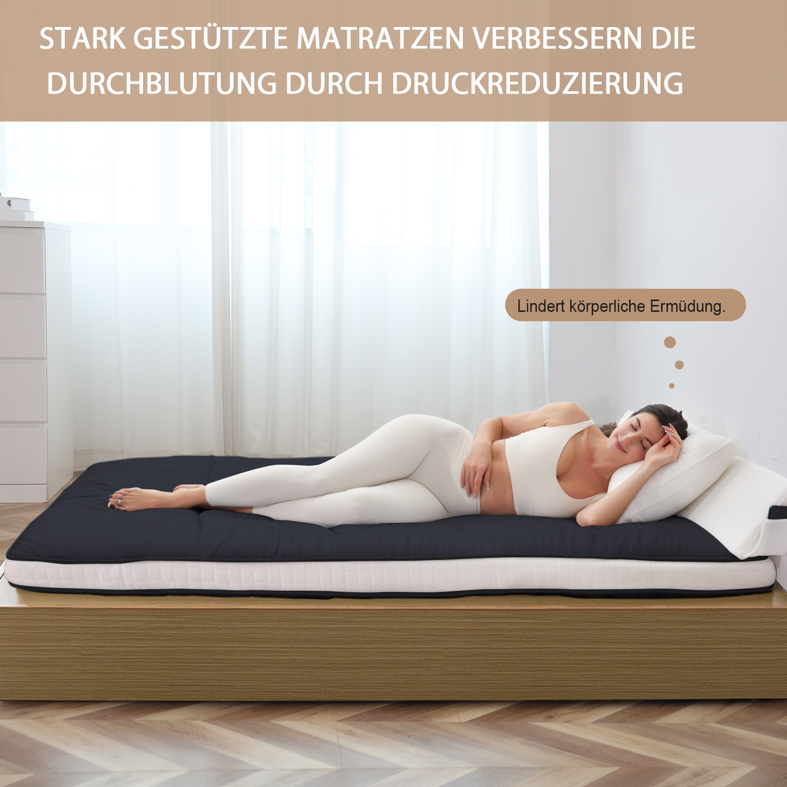 Eine Frau liegt auf einer dunklen Matratze auf einem Holzbett. Sie trägt weiße Kleidung.