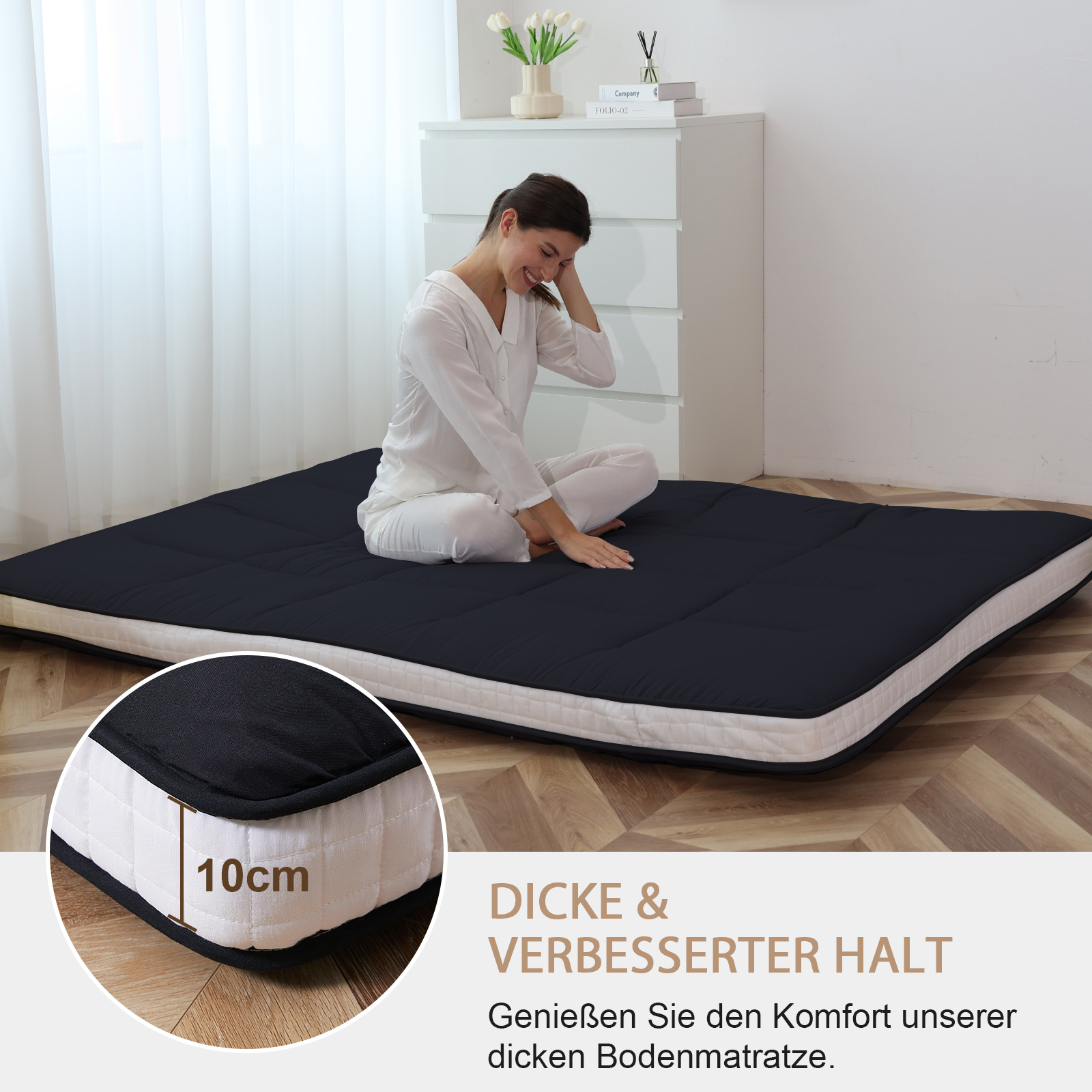 Eine Frau sitzt auf einer dunklen Matratze mit weißen Rändern. Nahaufnahme zeigt 10cm Dicke.
