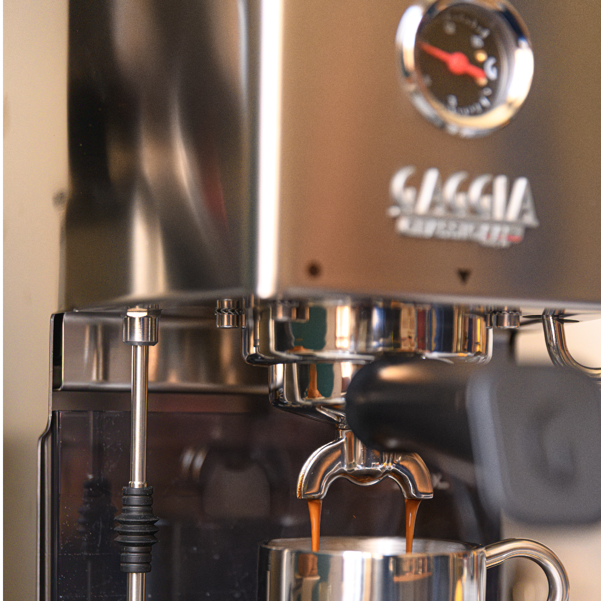 Espressomachine zet koffie in een metalen kop, stoompijpje zichtbaar.
