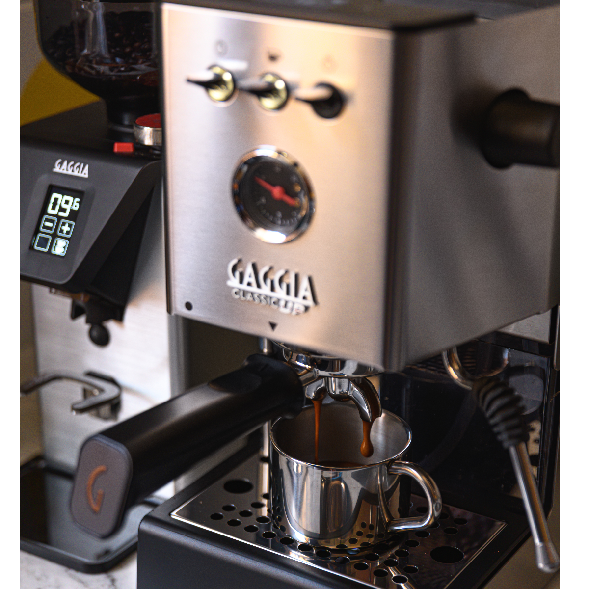Een Gaggia espressomachine zet koffie in een klein metalen kopje.