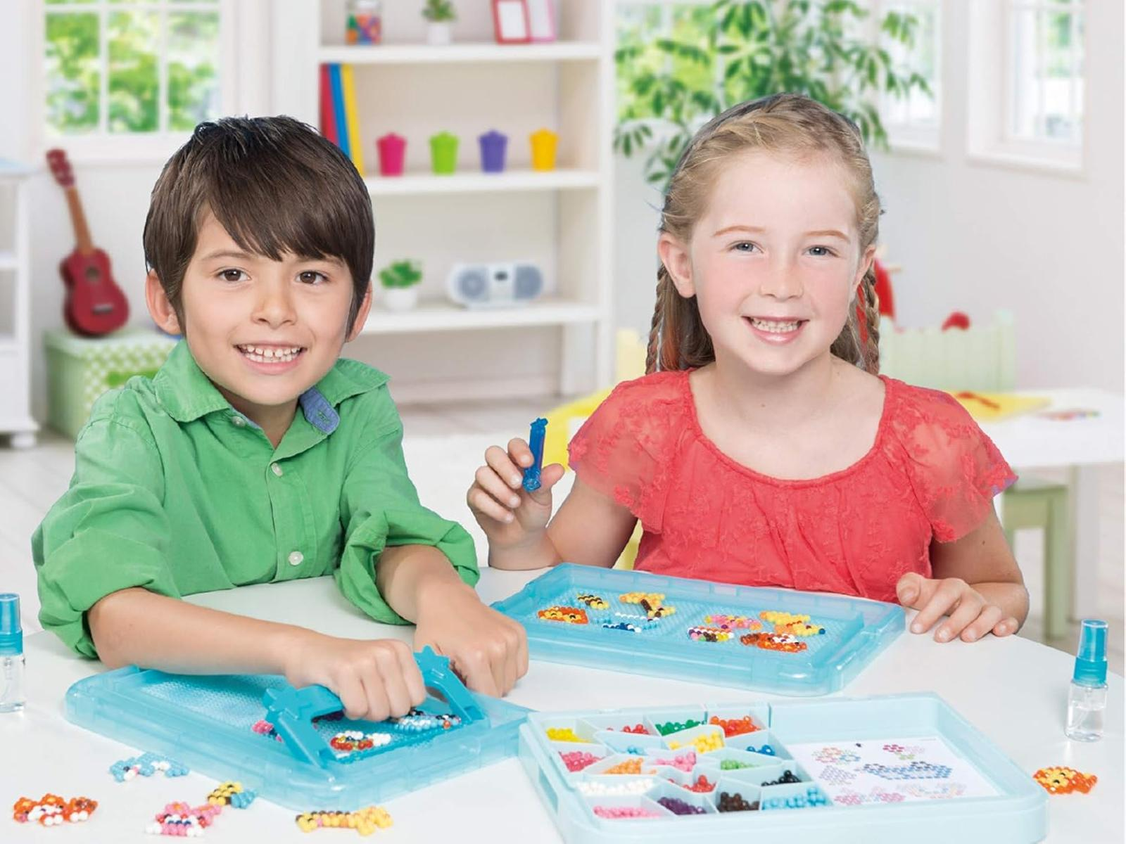 Zwei Kinder basteln mit bunten Perlen an Perlenbrettern.