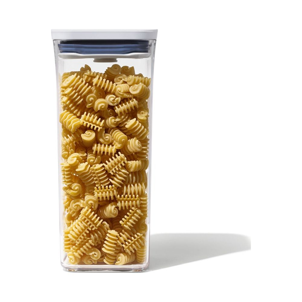 Un contenitore trasparente pieno di pasta rotini e coperchio bianco.