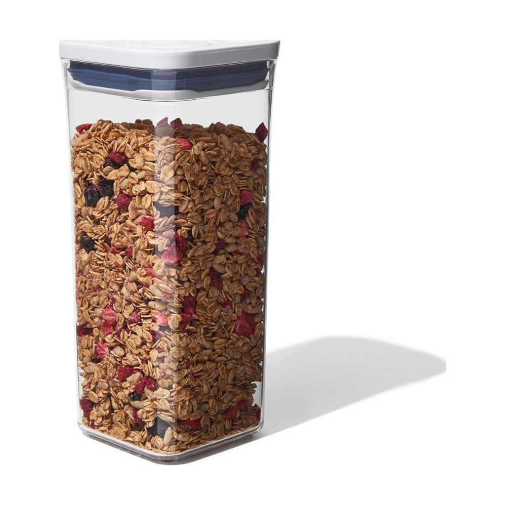 Un contenitore trasparente riempito di granola e frutti rossi.