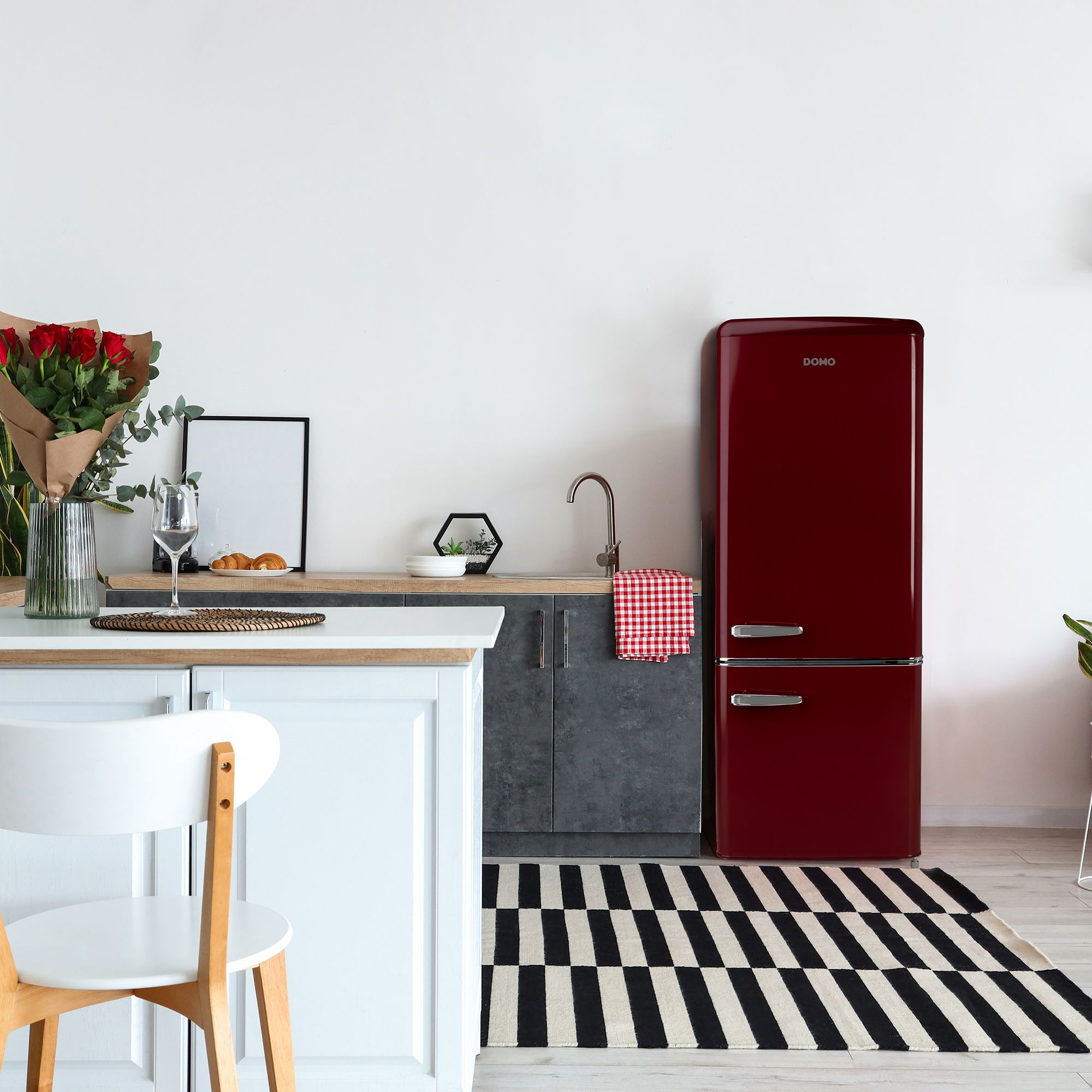 Frigorifero retrò rosso accanto al bancone della cucina con fiori e croissant.