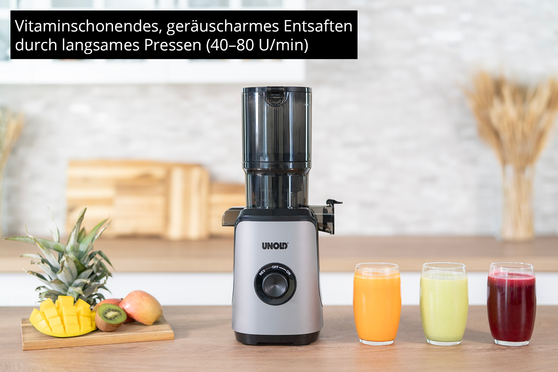Centrifuga argento con frutta e succhi su un tavolo di legno.