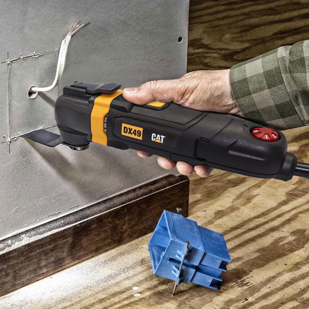 Bir el, metal kesmek için siyah bir CAT çok amaçlı alet kullanıyor. Yakında mavi bir parça var.