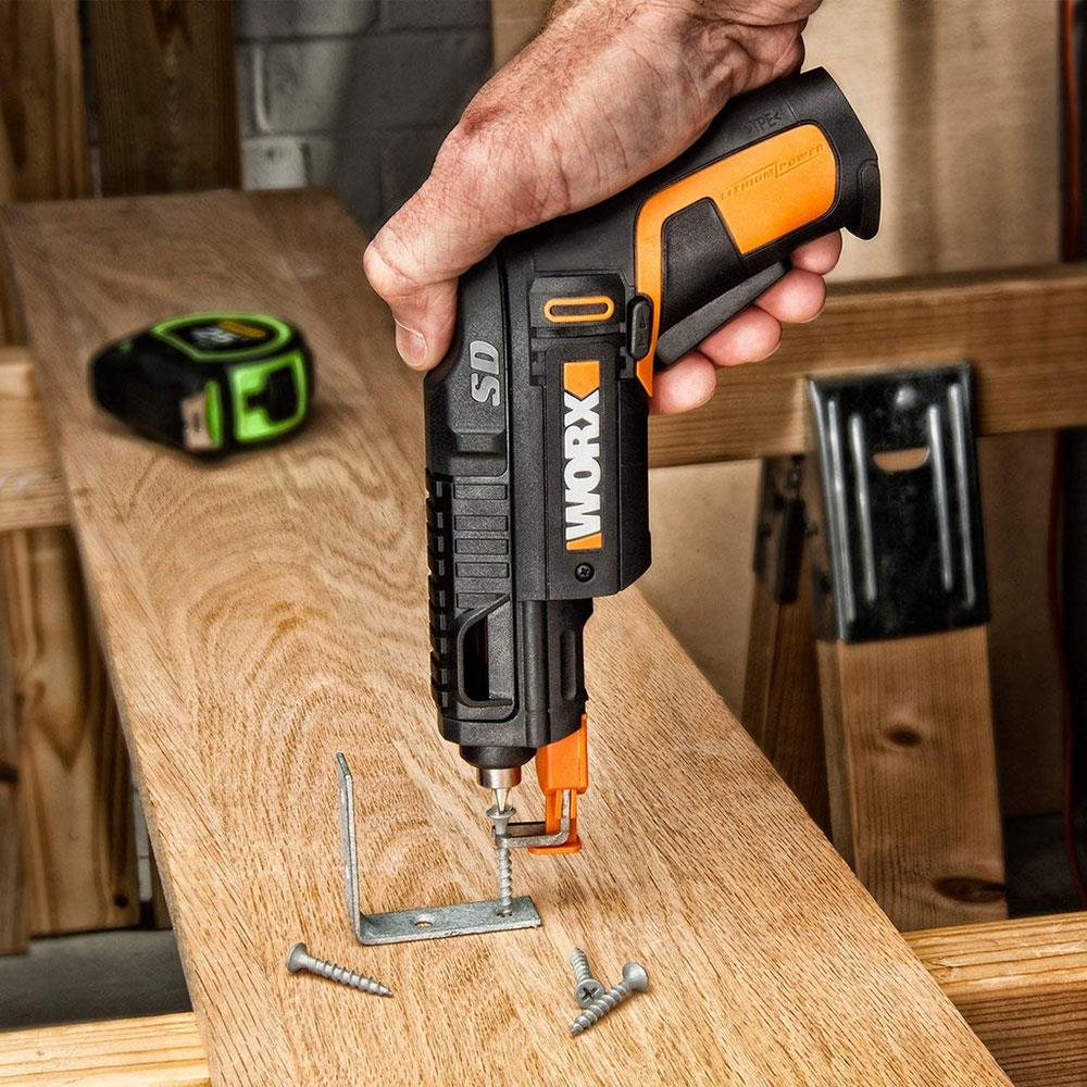 Eine Hand hält einen schwarzen und orangen Akkuschrauber, der eine Schraube in Holz dreht.