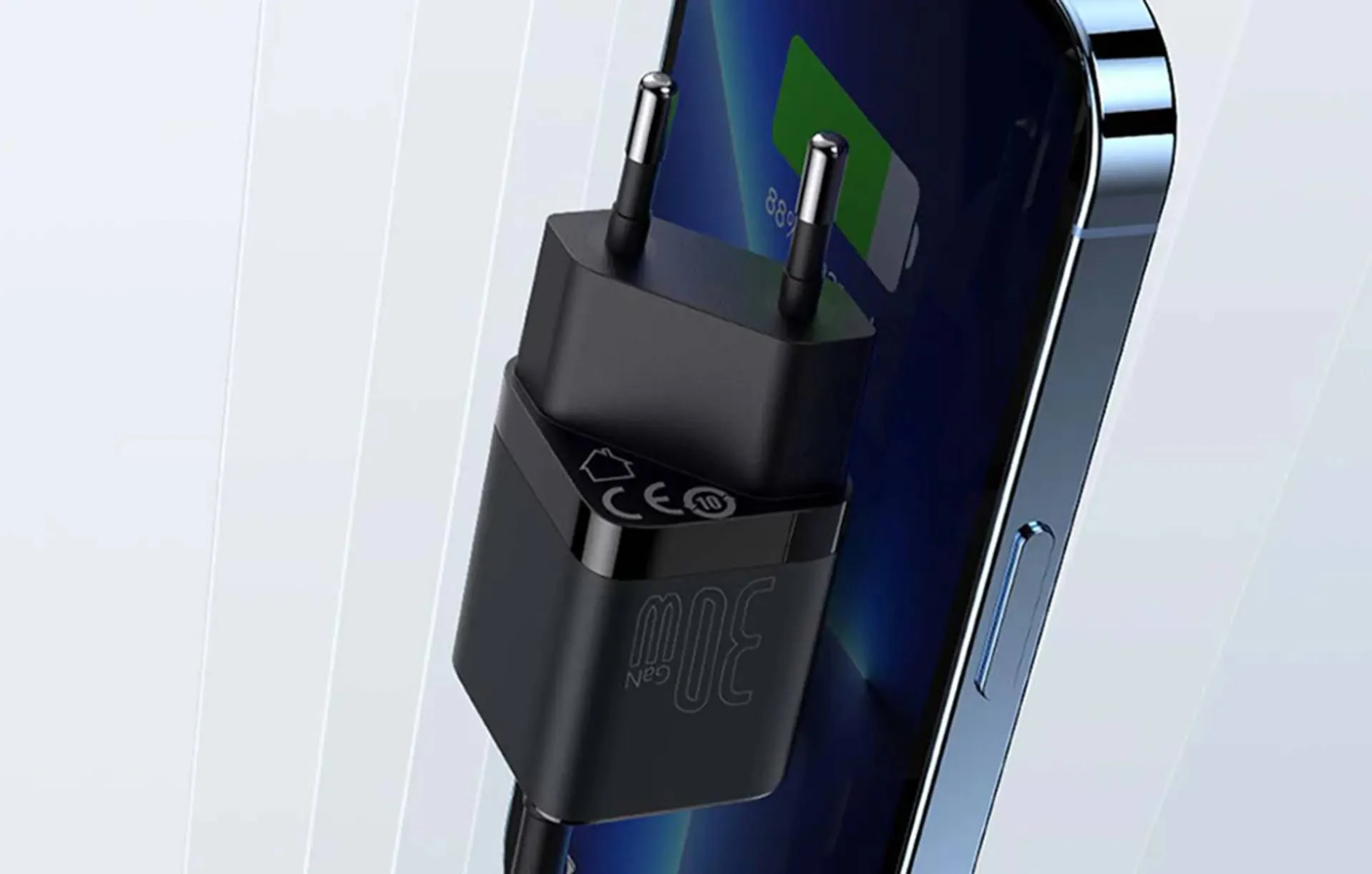 Una spina di ricarica USB-C nera con due pin è inserita accanto a uno smartphone.