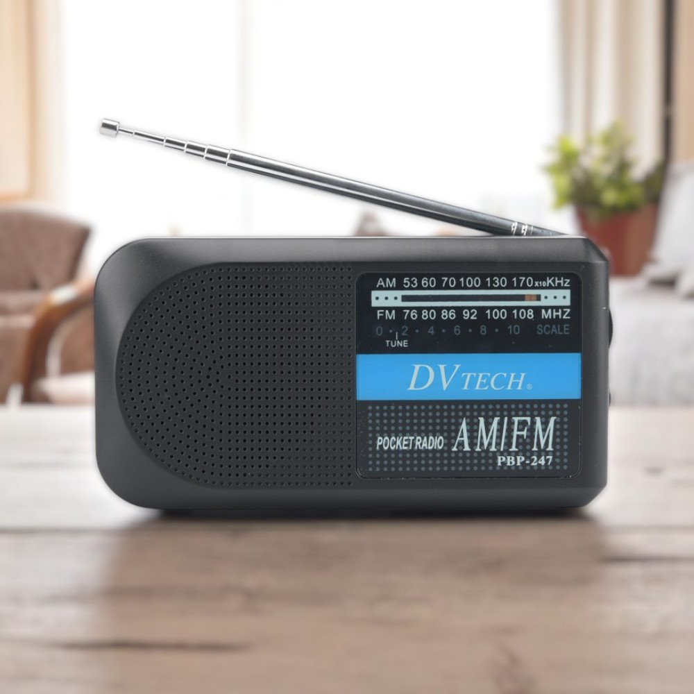 Una radio de bolsillo DVTech AM/FM negra con antena extendida sobre una mesa de madera.