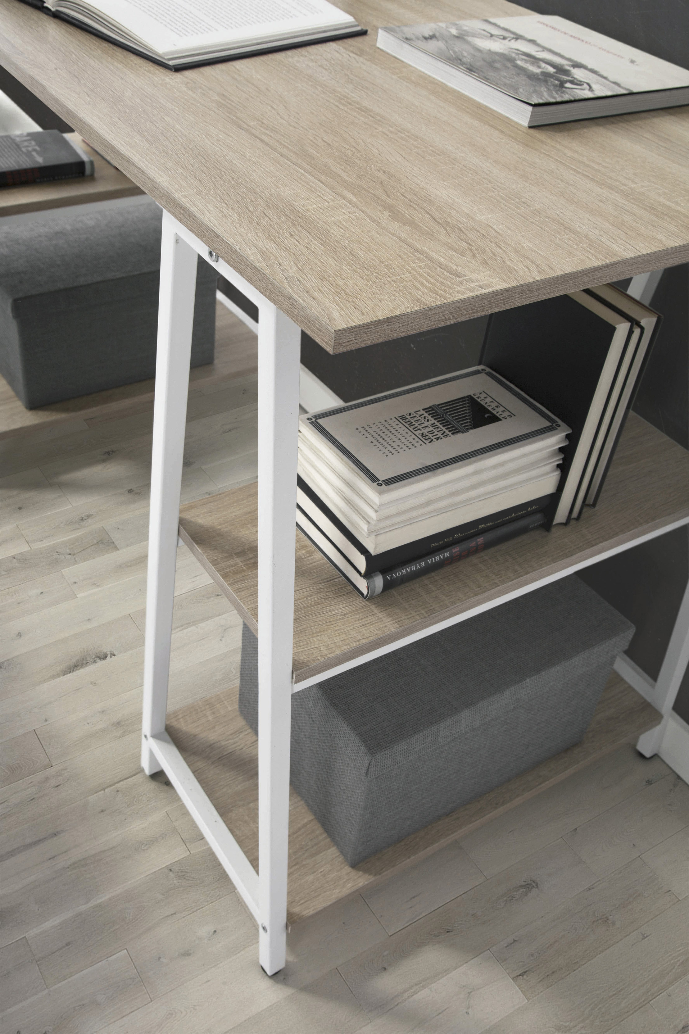 Un escritorio con tapa de madera, patas blancas y libros en los estantes.