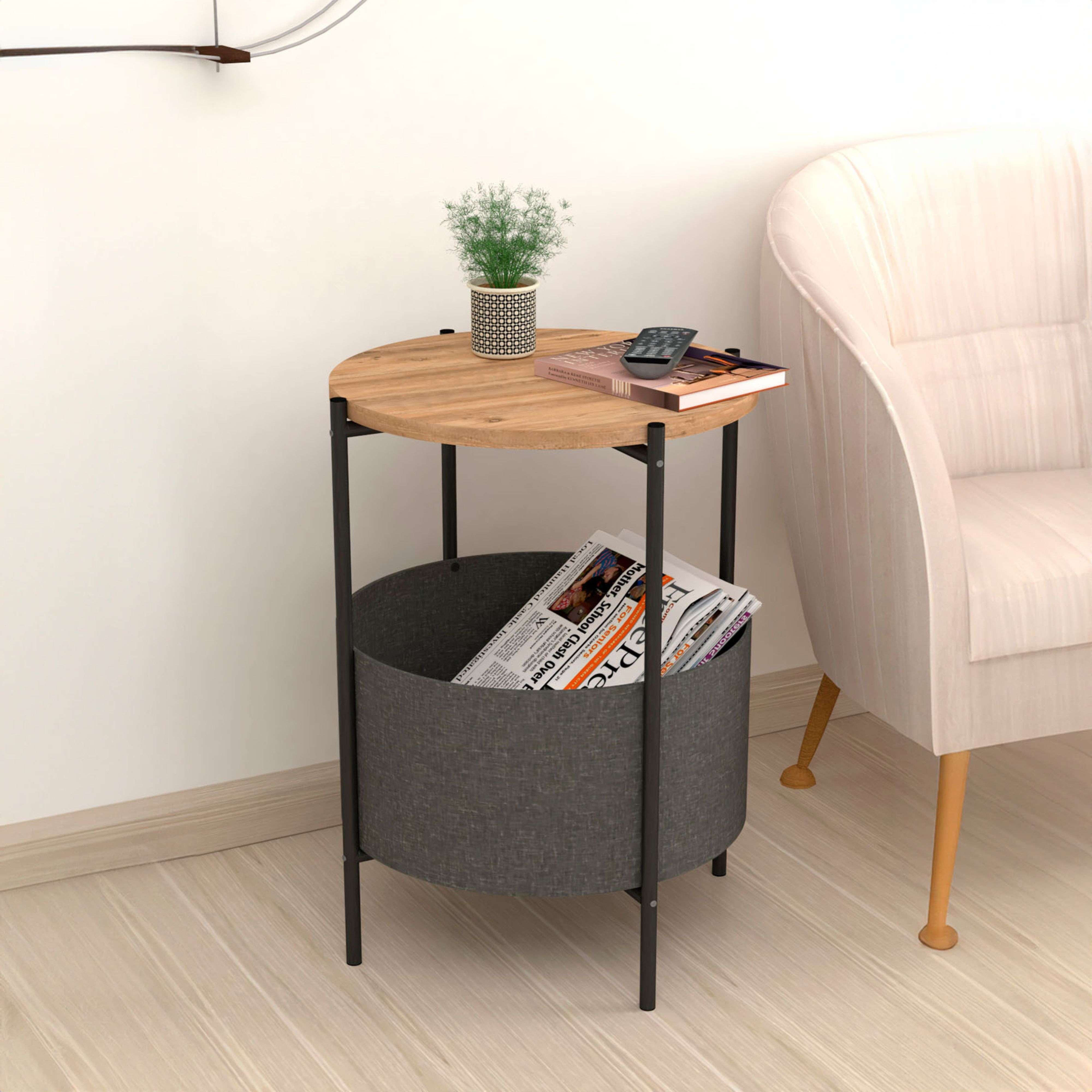 Mesa redonda de madera con periódicos, libro, mando, planta y sillón.