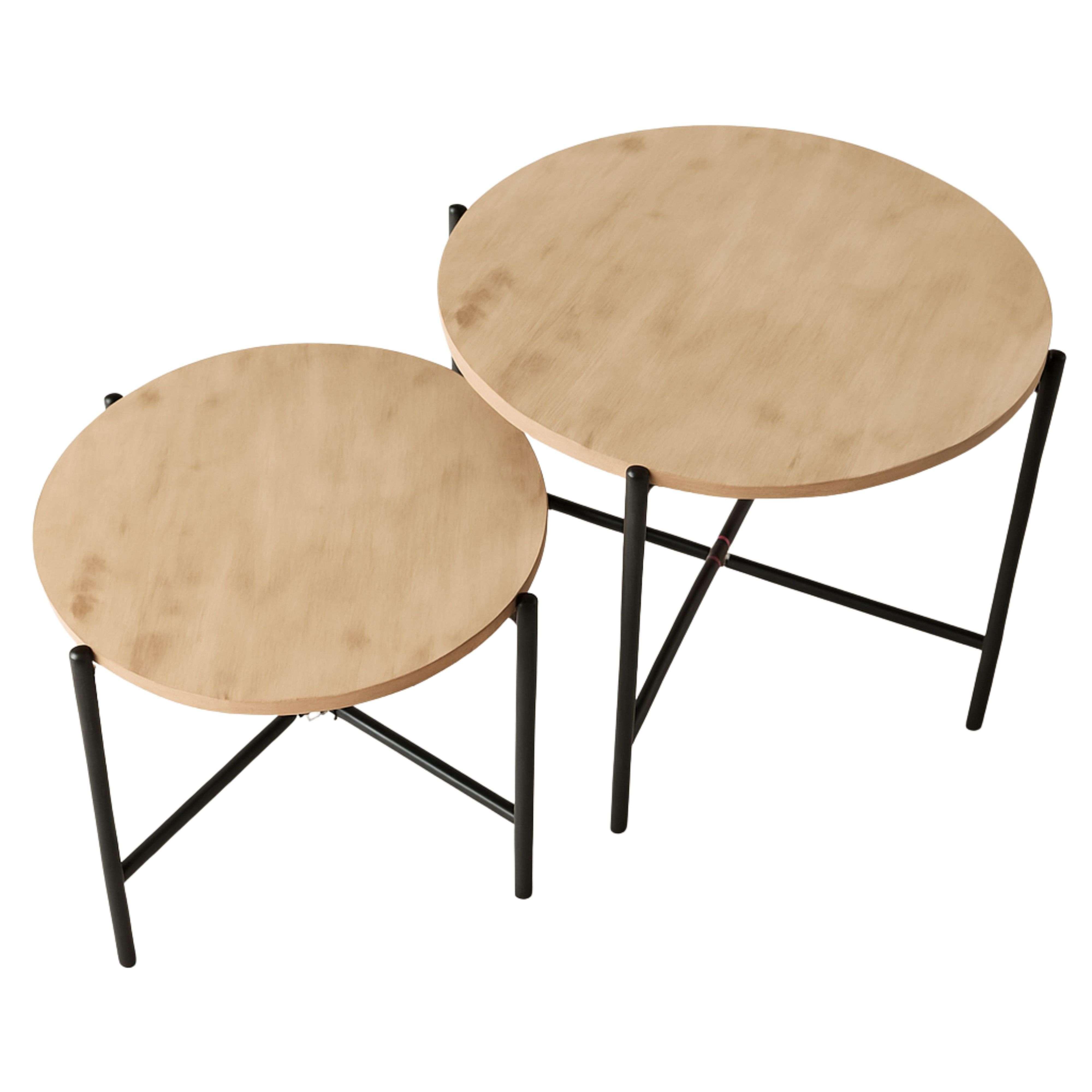 Dos mesas redondas de madera con patas de metal negro, una al lado de la otra.
