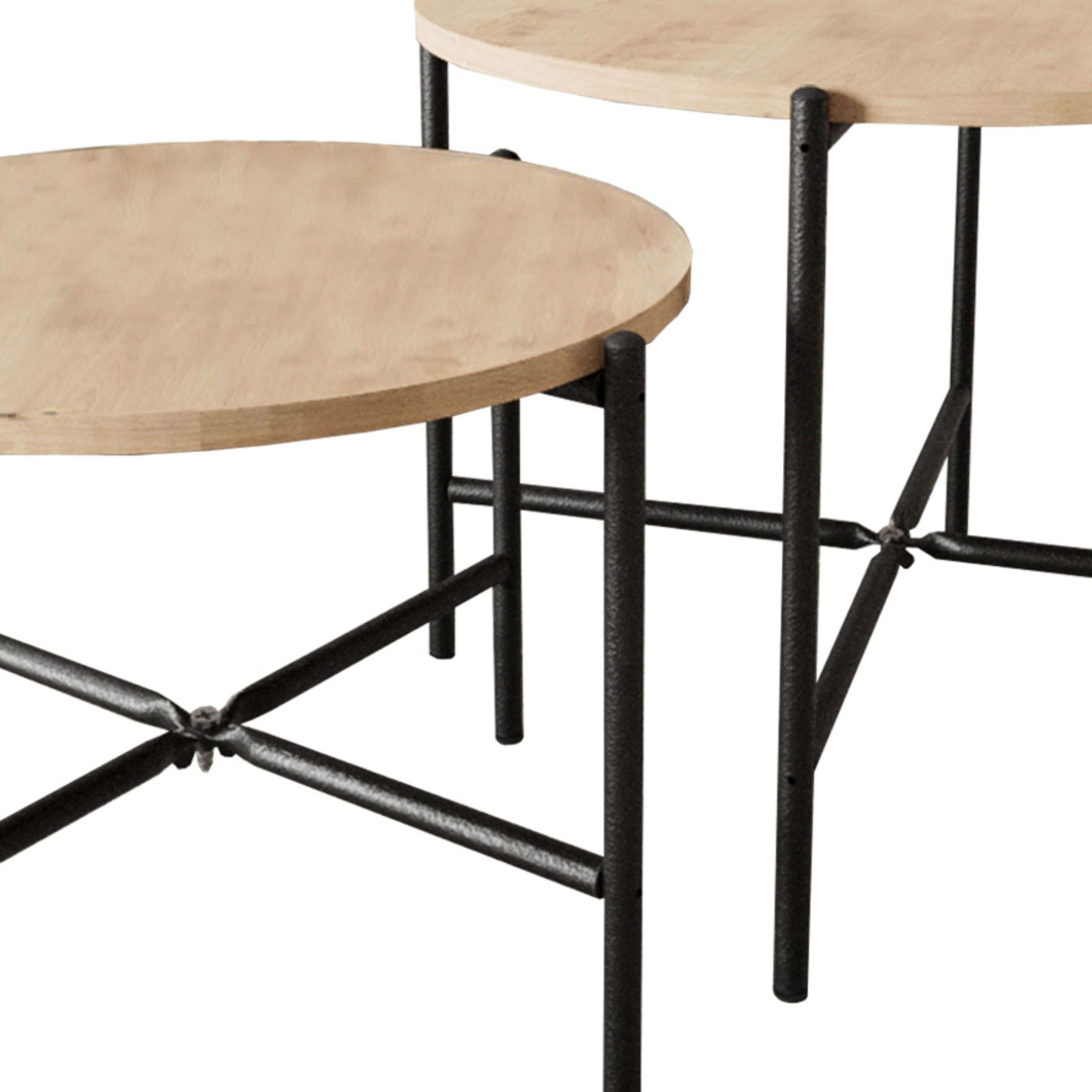 Dos mesas redondas de madera con patas de metal negro una al lado de la otra.