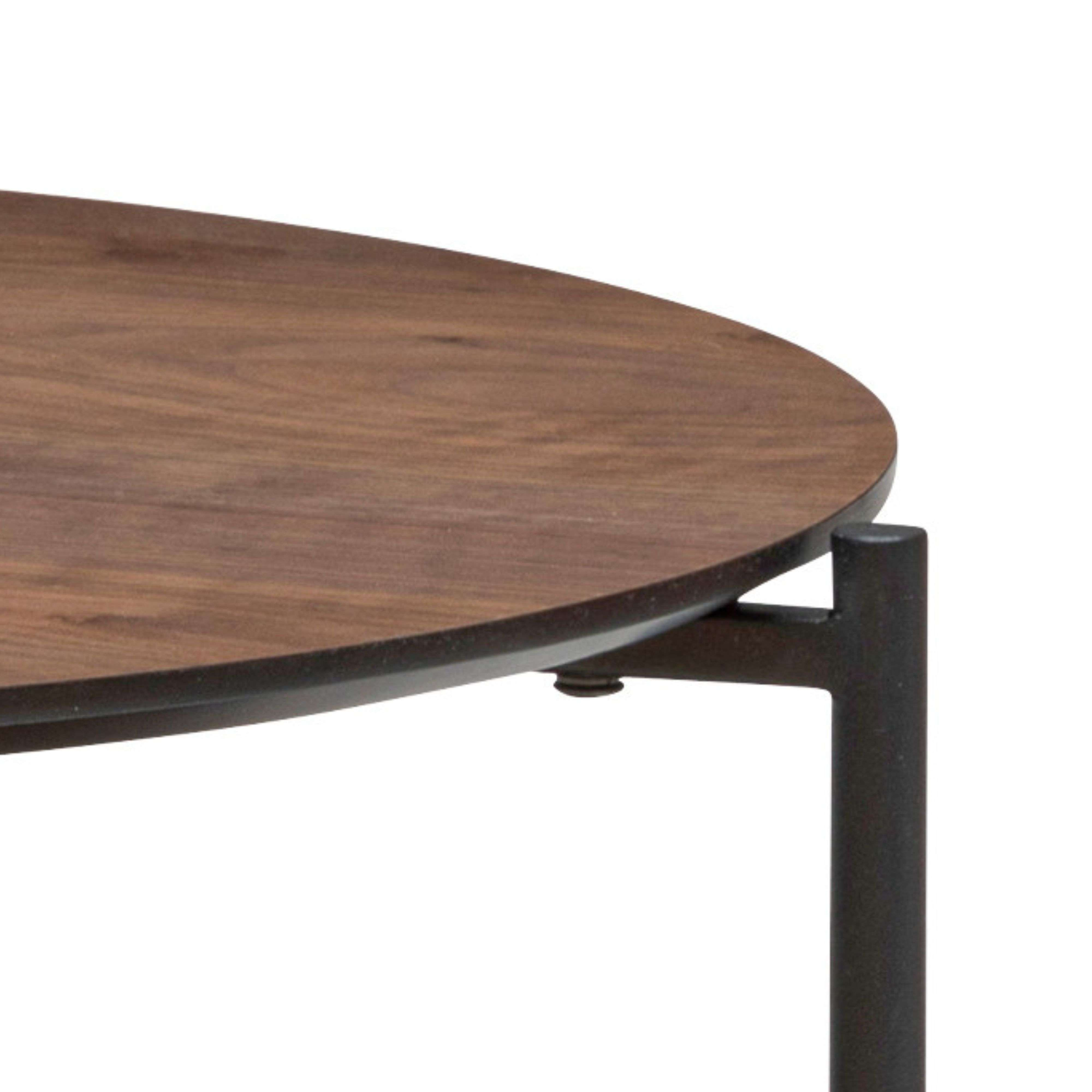 Tablero redondo de madera con pata de metal oscuro.