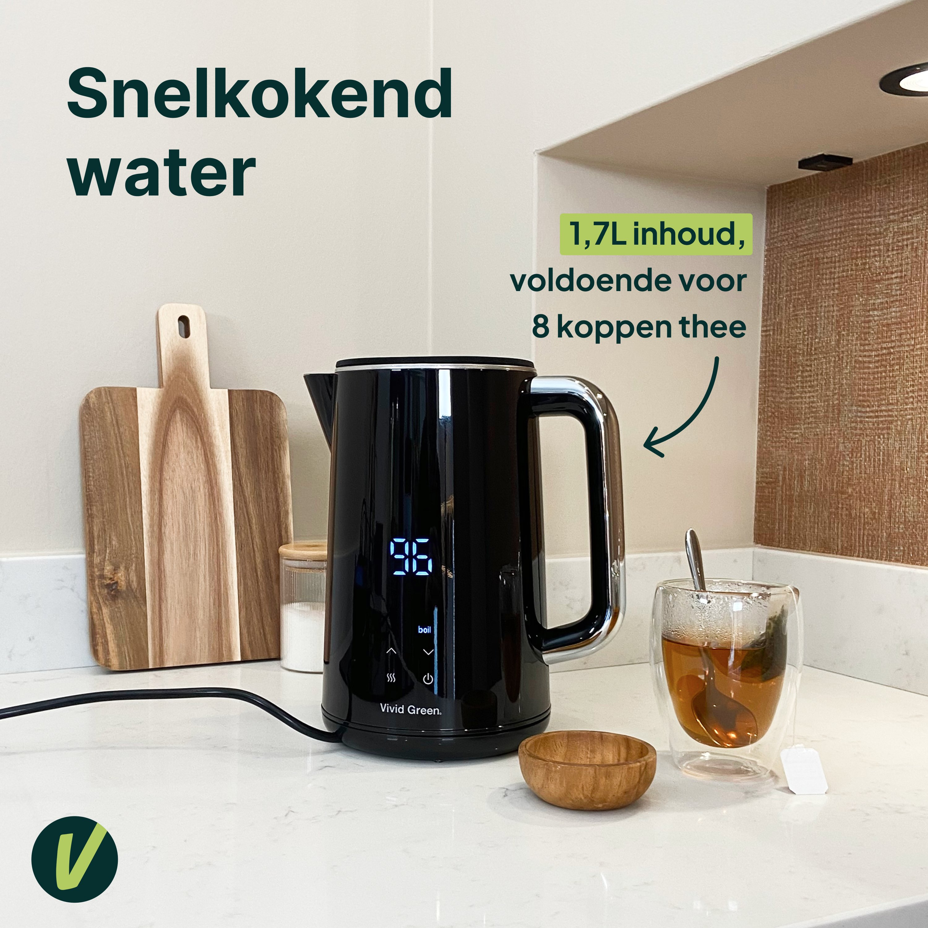 Een zwarte waterkoker toont 96 graden. Een glas thee staat ernaast.